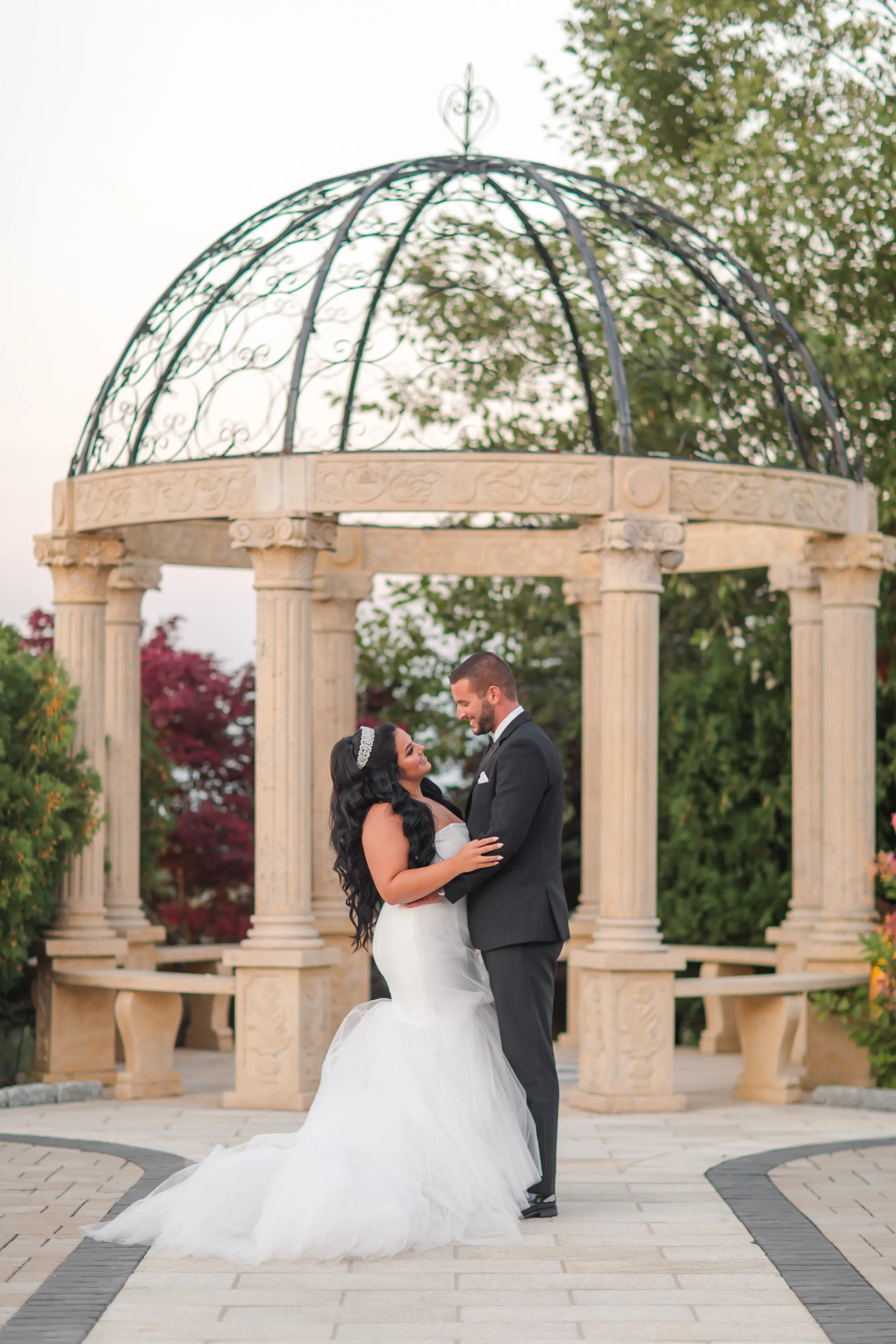 Groom and Bride Wearing Simple Mermaid Wedding Dress Called Holden By Sottero And Midgley Next To A Pavilion Looking At Each Other