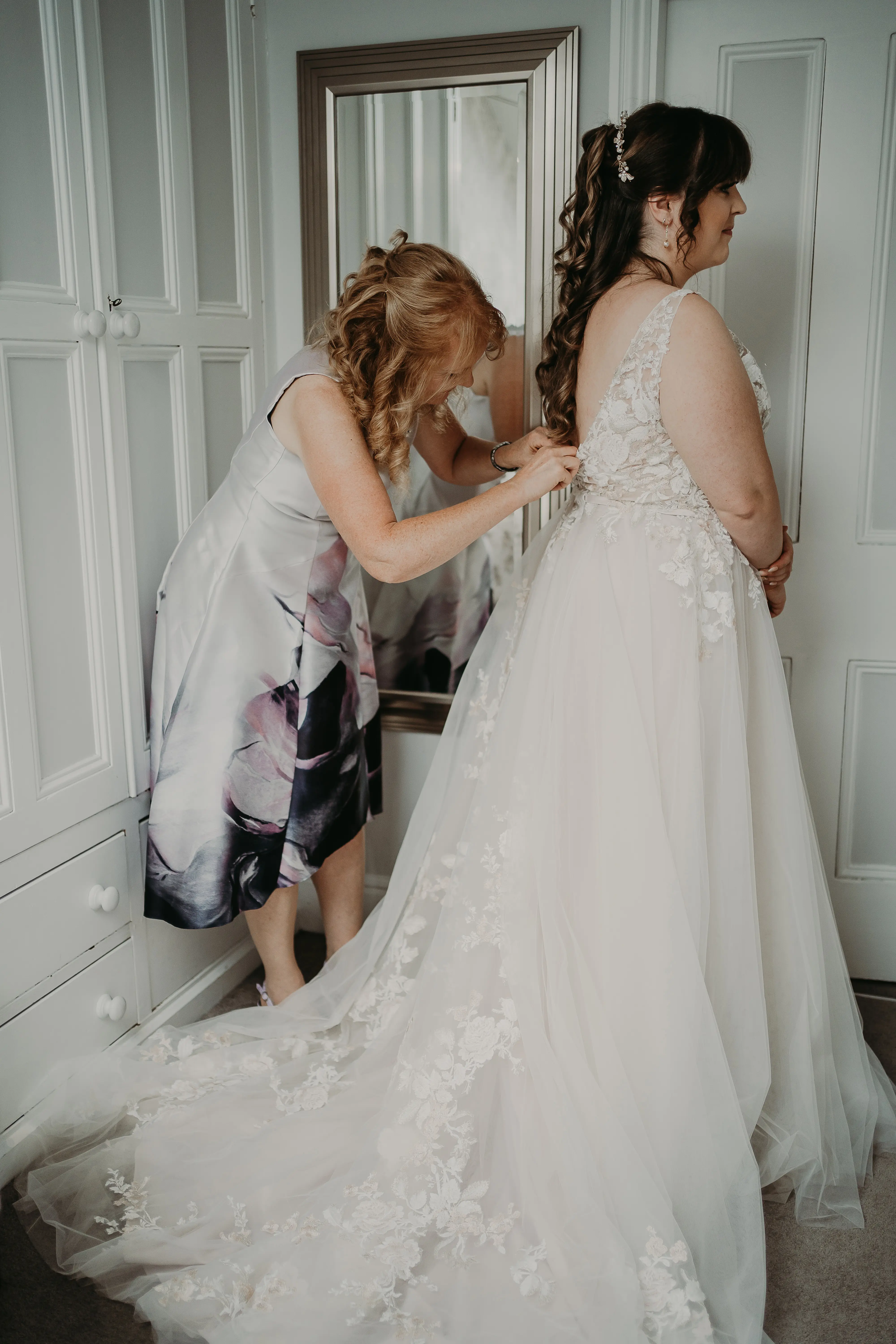 Mother of the bride fastening the back of wedding dress called Minerva.