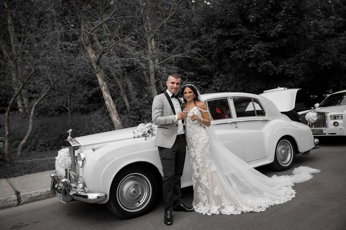 Bride Wearing Lace Sheath Wedding Dress Called Tuscany Lynette By Maggie Sottero With Groom In Front Of Vintage Car