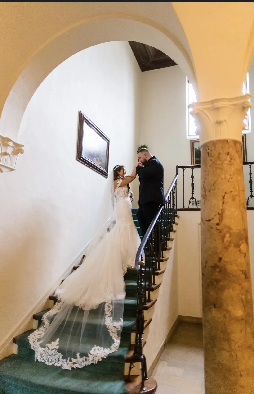 Bride wearing Lennon wedding dress by Maggie Sottero walking up stairs with her husband