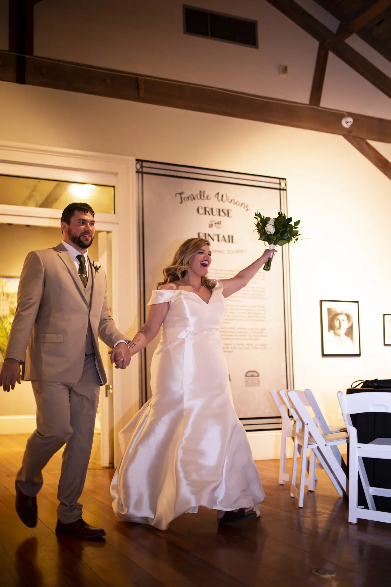 Bride And Groom Reception Entrance. Bride Wearing Vintage Glamour Timeless Off-The-Shoulder Fit-And-Flare Wedding Dress Called Josie By Rebecca Ingram