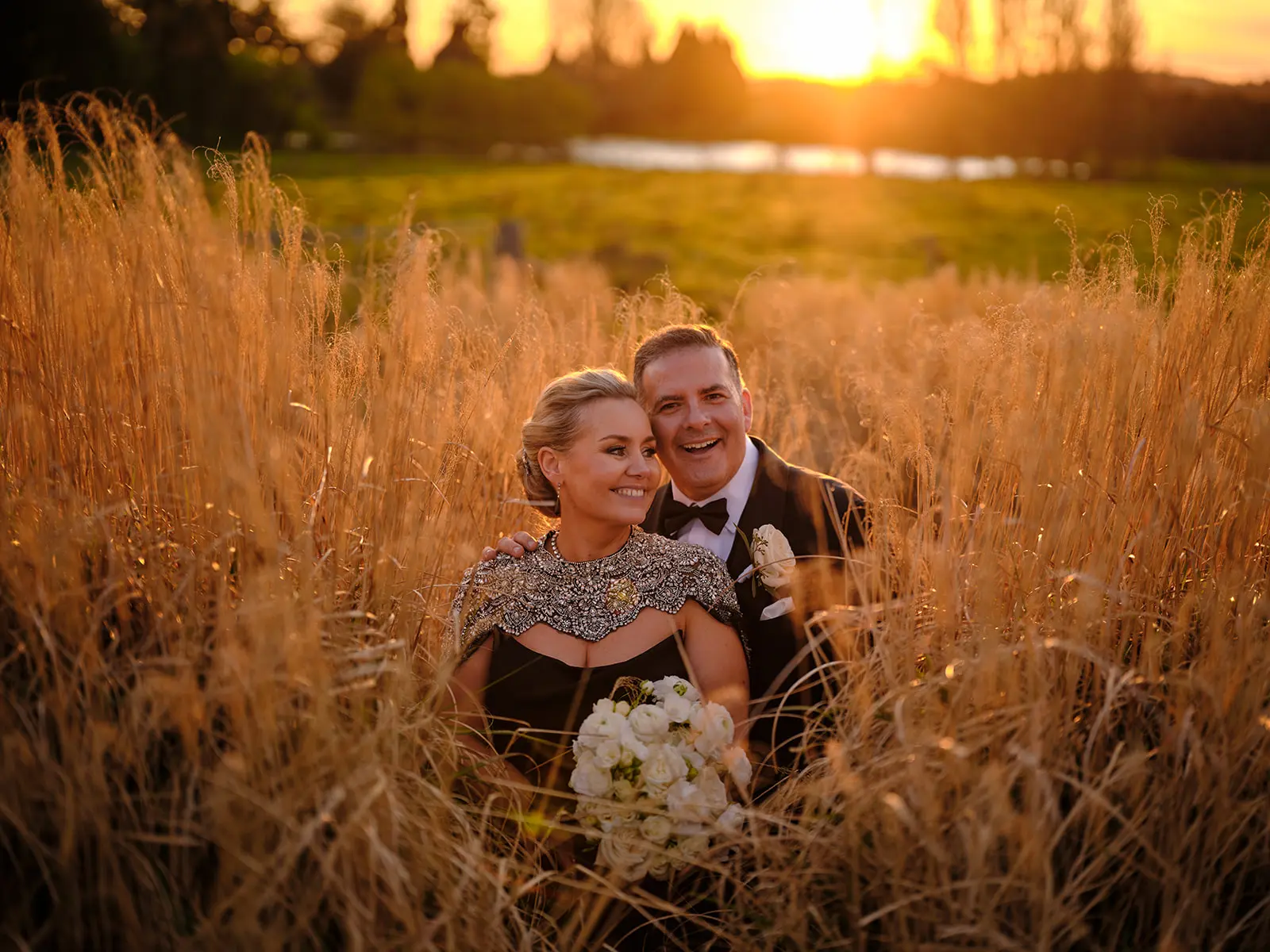 Bride wearing Aspen by Sottero and Midgley sitting in a field with her husband