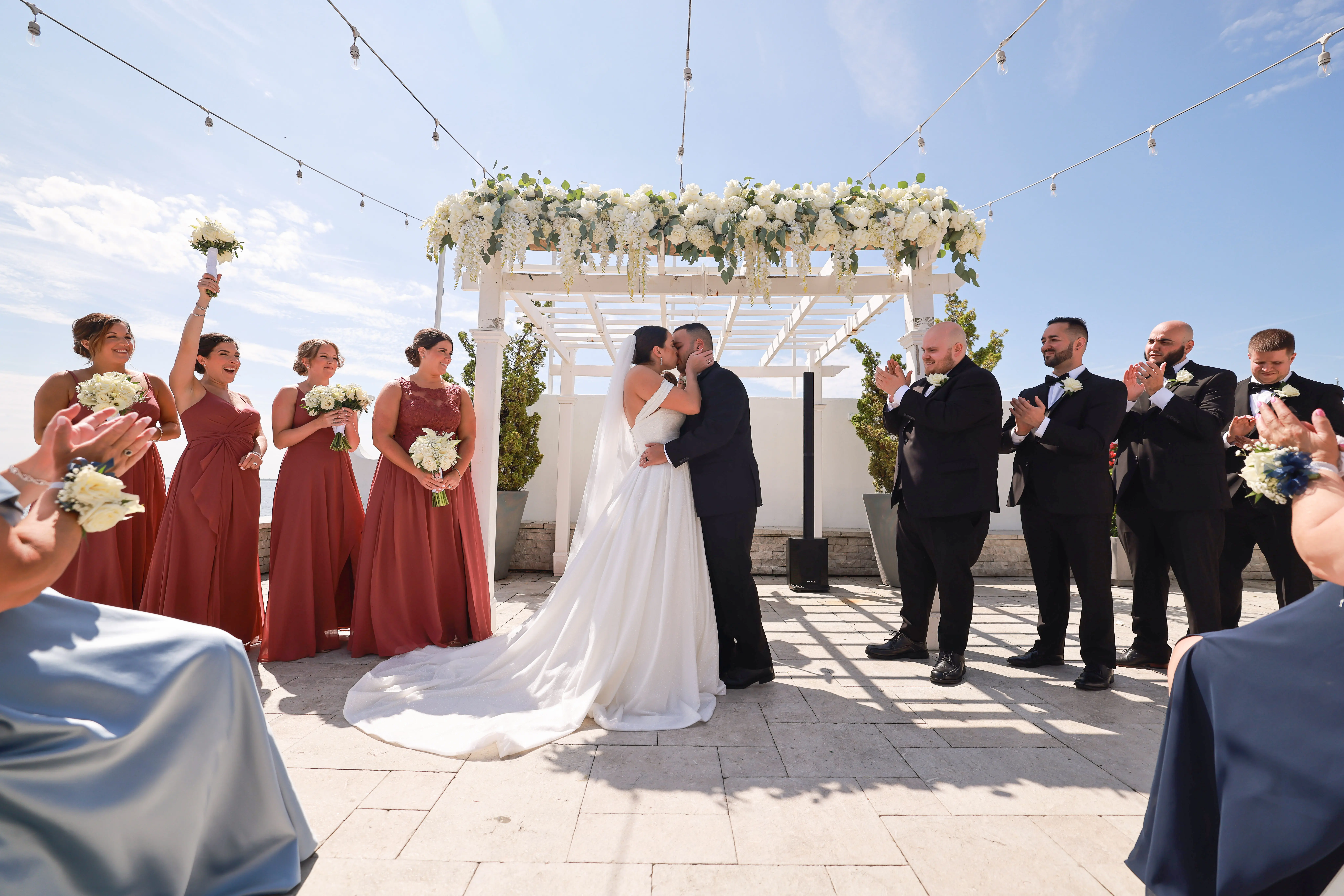 Bride wearing Anniston wedding dress by Sottero and Midgley kissing under the arch