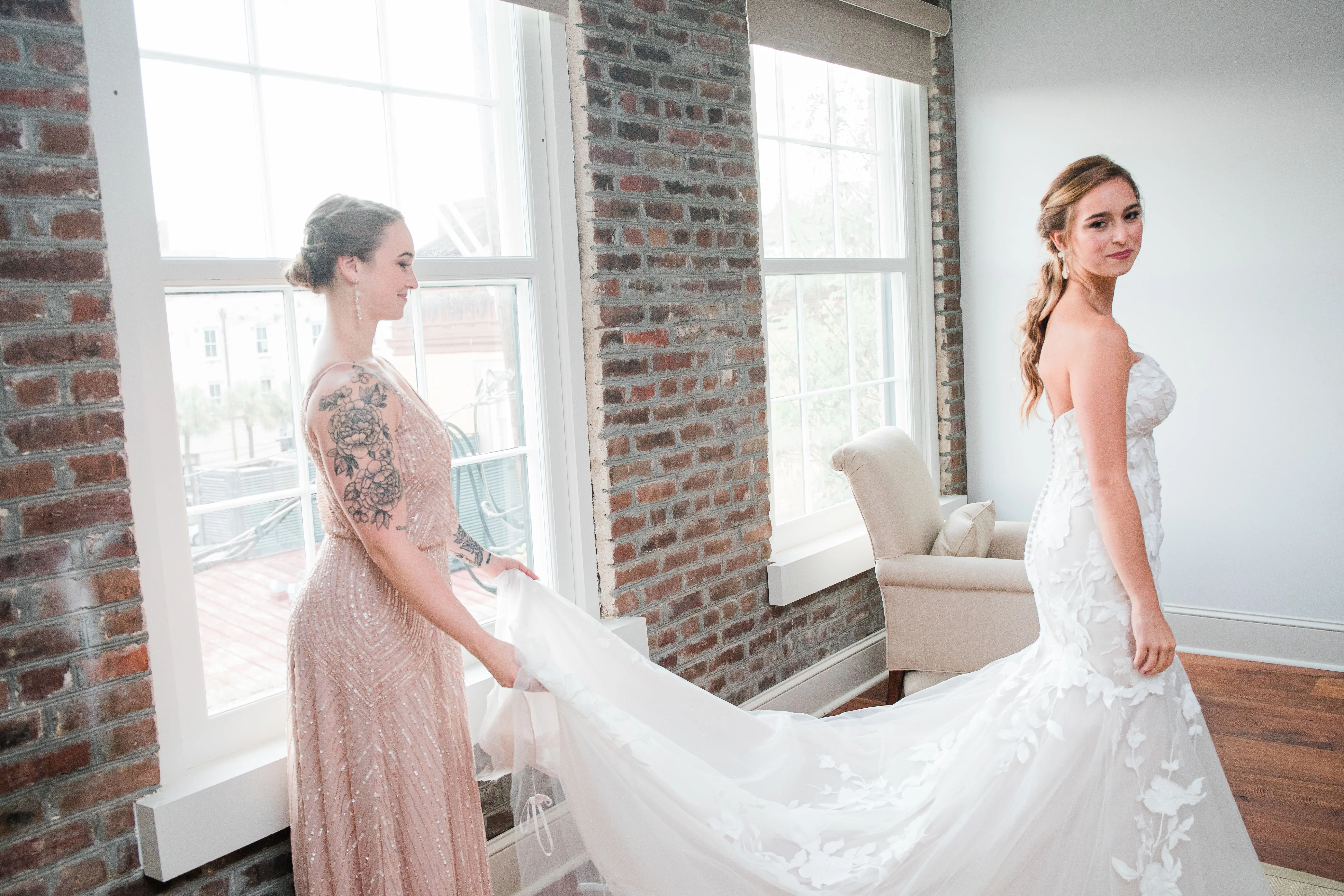 Bride with bridesmaid wearing strapless mermaid wedding dress with oversized lace