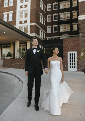 Bride wearing Mitchell wedding dress by Maggie Sottero holding hands with her husband
