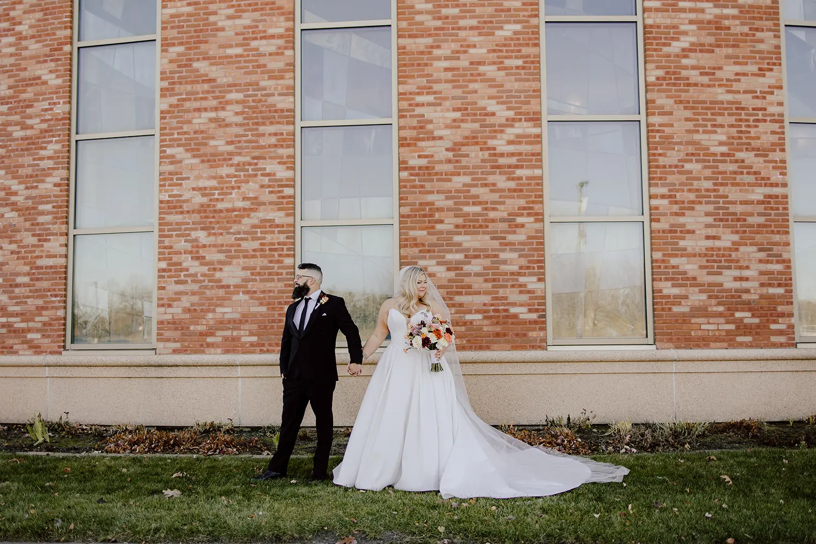 Bride wearing Derrick by Maggie Sottero and her husband outside of their venue