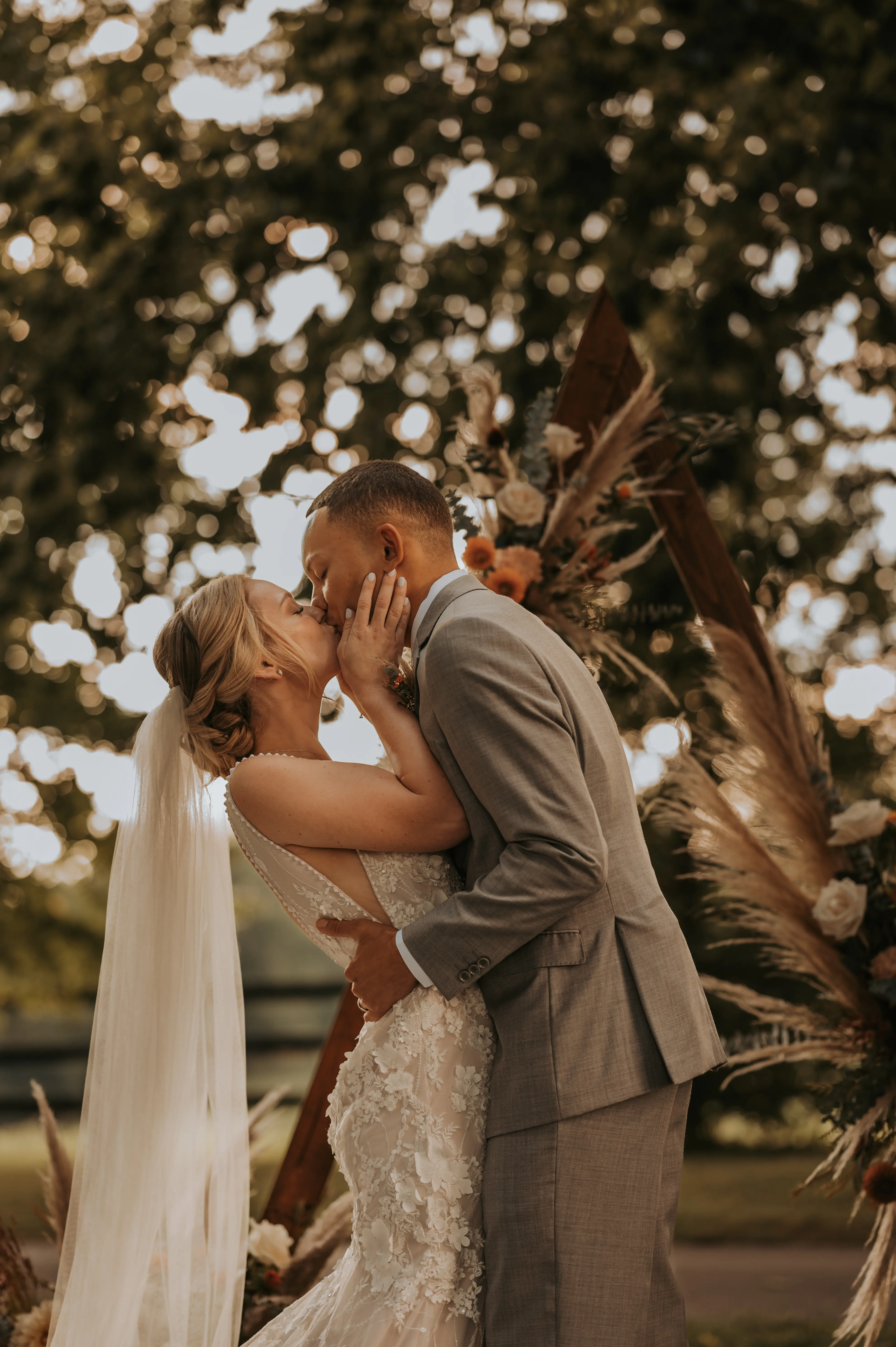 Groom Kissing Bride in Mermaid Wedding Dress with 3-D Floral Motifs and Extended Scalloped Lace Train Called Cruz by Sottero & Midgley