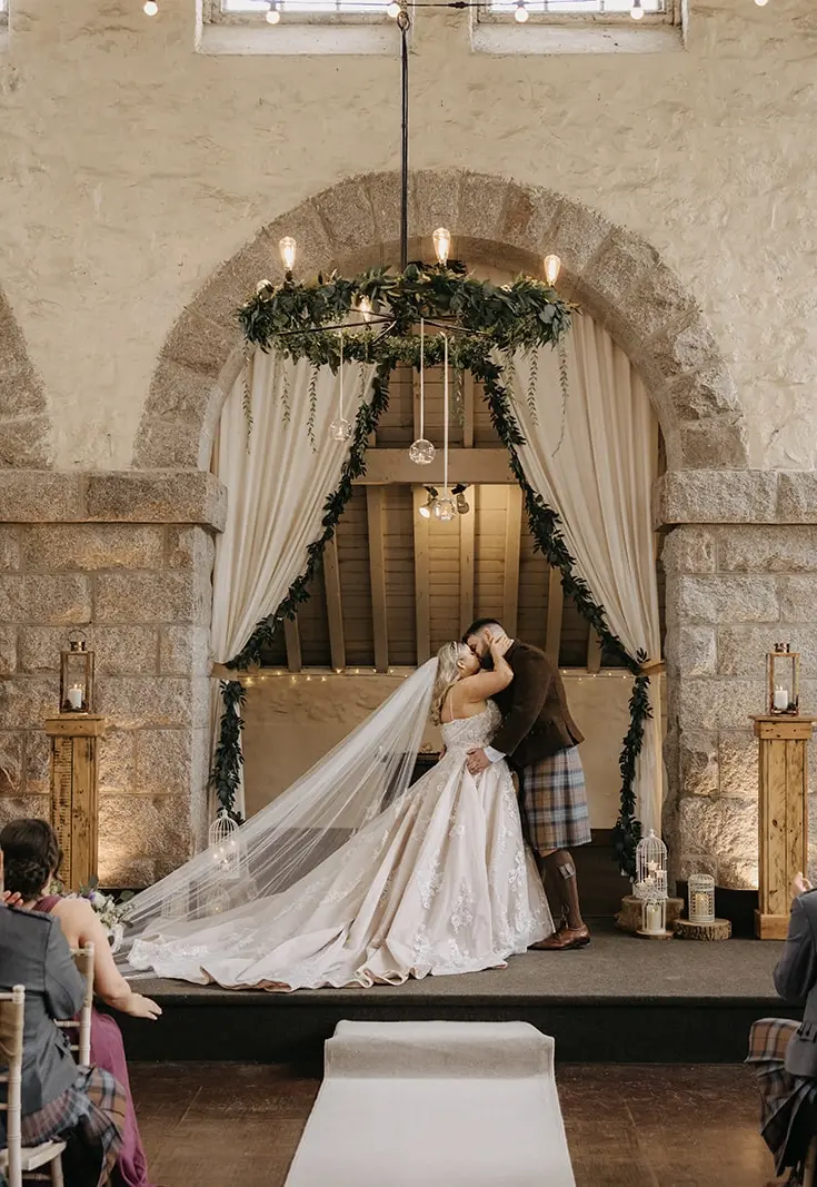 Bride wearing Norvinia by Sottero and Midgley kissing her husband during their ceremony