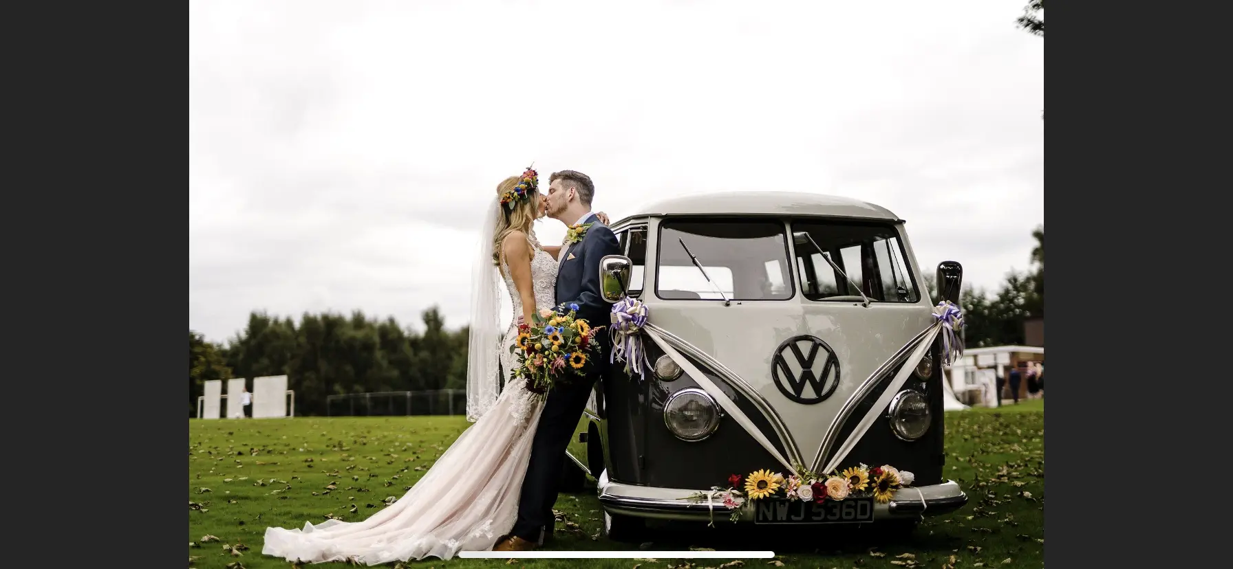 Groom and Bride Standing next to Volkswagen Van Wearing Elegant Fit-and-Flare Bridal Dress by Maggie Sottero