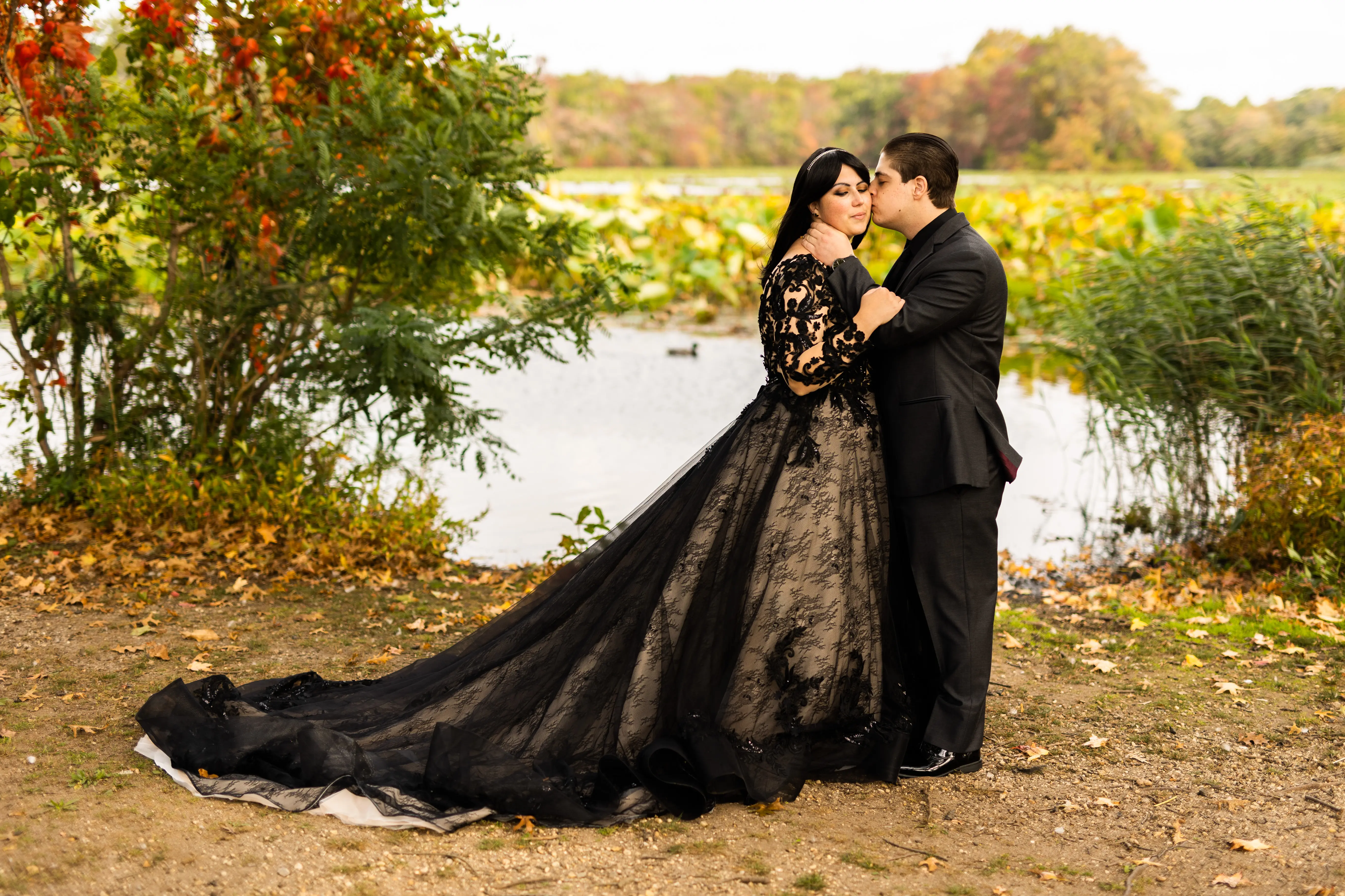 Bride in a Field with Groom Wearing Long Sleeve Black Lace Ballgown Wedding Dress.