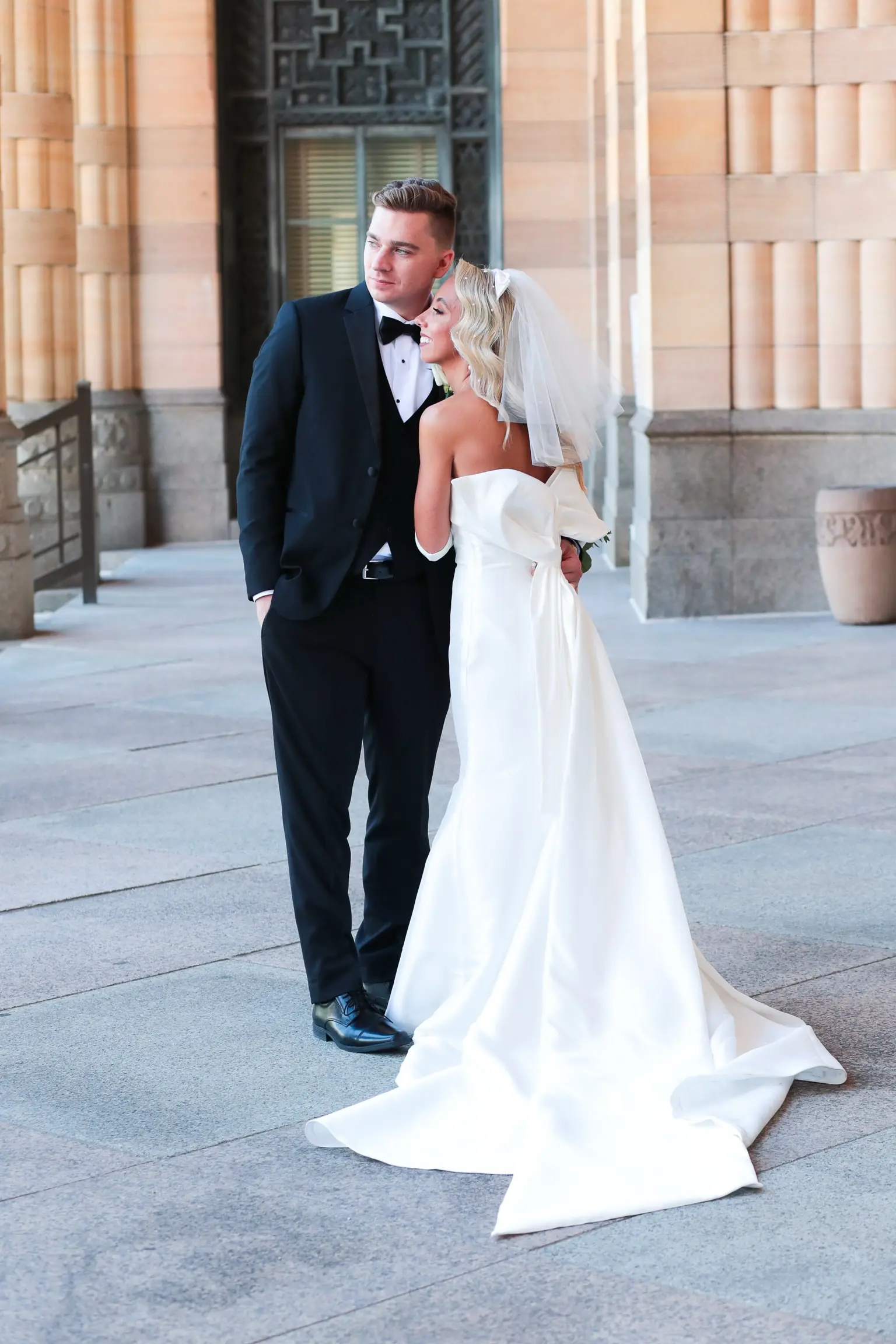 Bride In 90's Inspired Wedding Dress Called Mitchell By Maggie Sottero with Groom, Bridal Gloves, And Wedding Veil