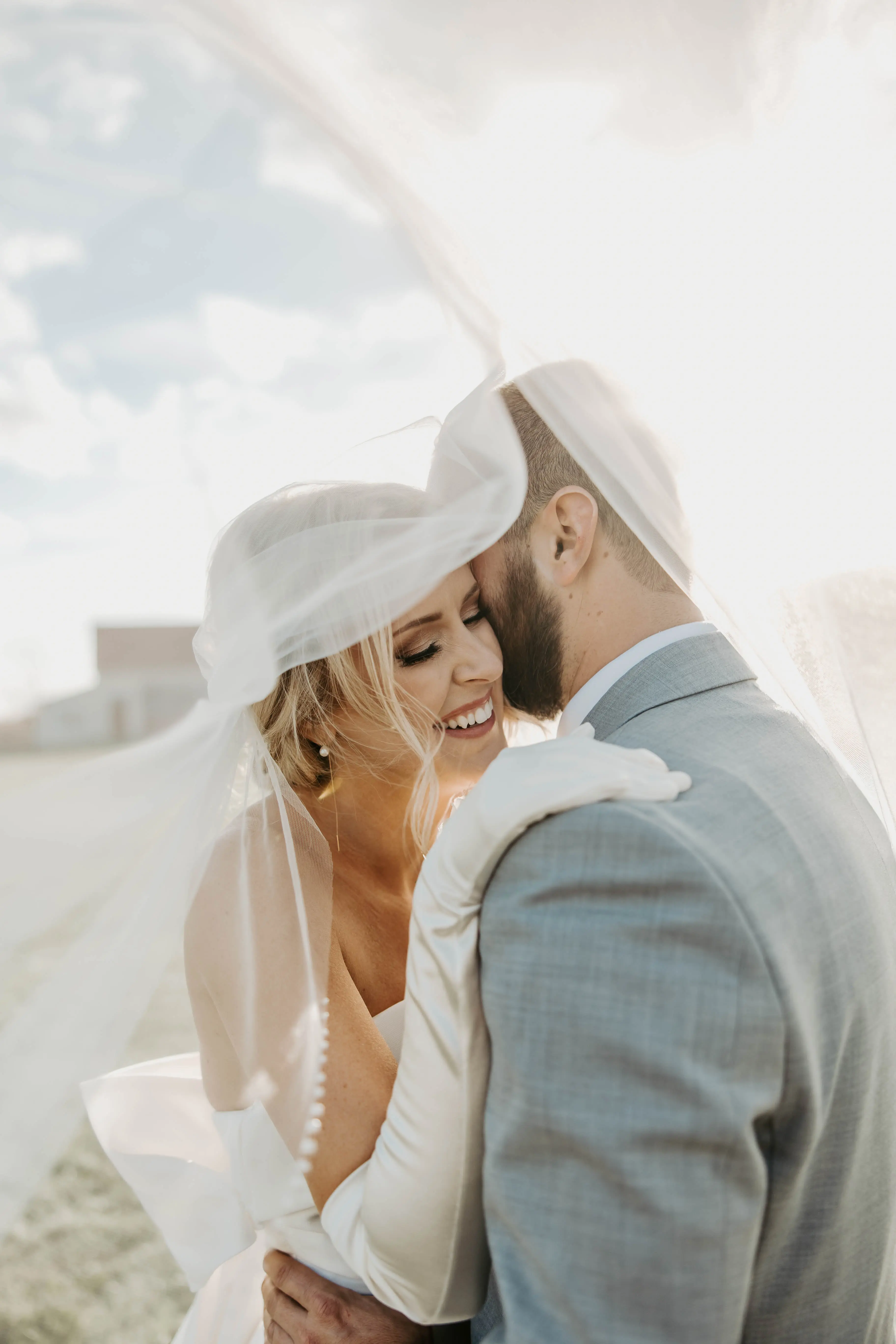 Groom Smiling With Bride In A White Strapless Wedding Dress Named Mitchell By Maggie Sottero