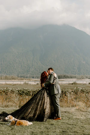 Bride Wearing Black Wedding Dress Zander By Sottero and Midgley Kissing Groom In A Field