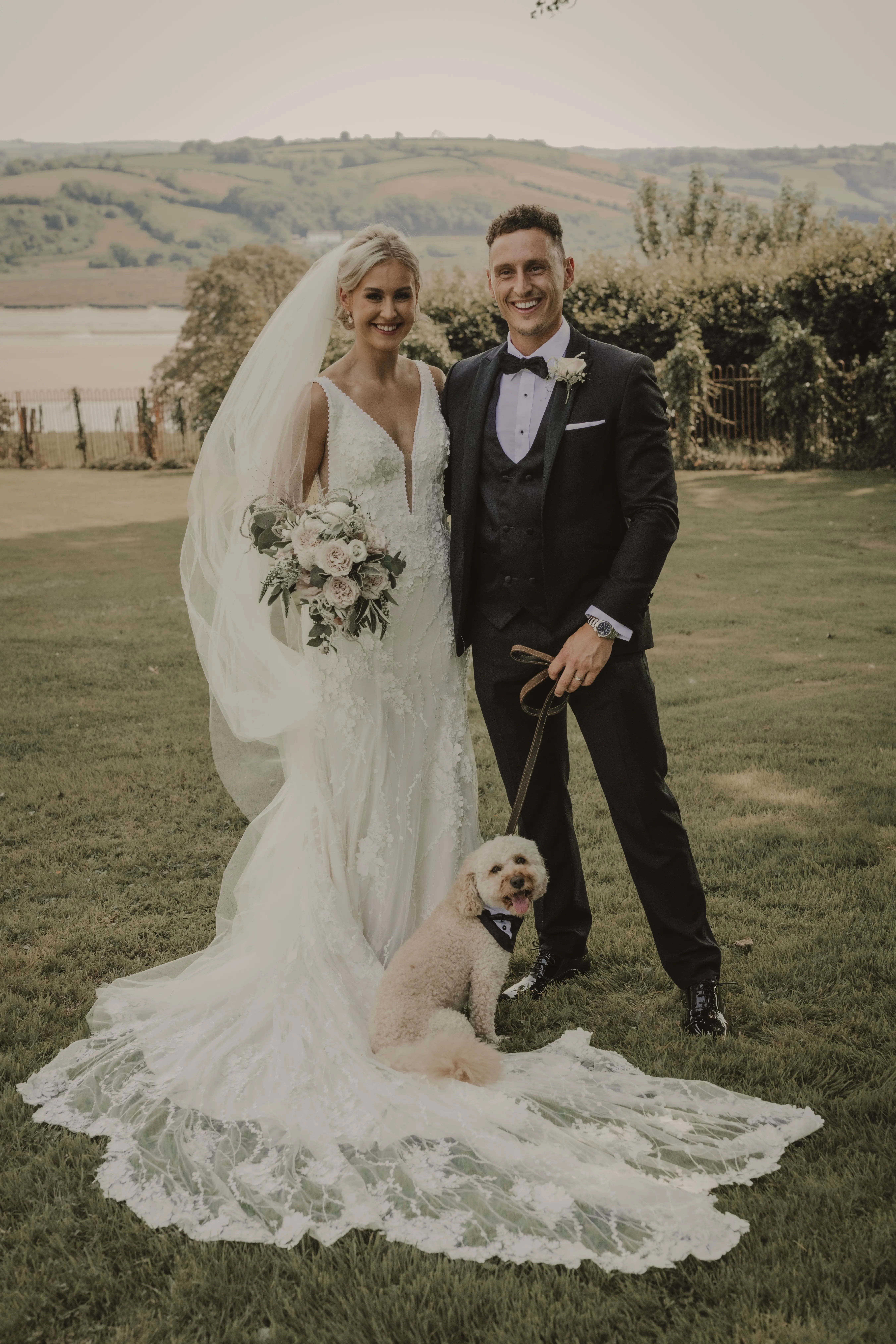 Groom, Pup, and Beautiful Bride in Vintage-Inspired Mermaid Wedding Dress with 3-D Floral Motifs and Extended Scalloped Lace Train Called Cruz by Sottero & Midgley