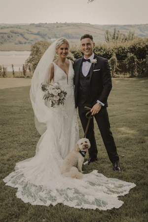 Groom, Pup, and Beautiful Bride in Vintage-Inspired Mermaid Wedding Dress with 3-D Floral Motifs and Extended Scalloped Lace Train Called Cruz by Sottero & Midgley