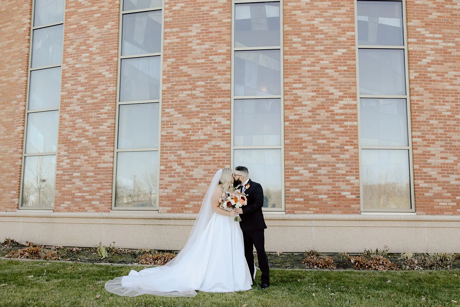 Bride wearing Derrick by Maggie Sottero kissing her husband outside of their venue
