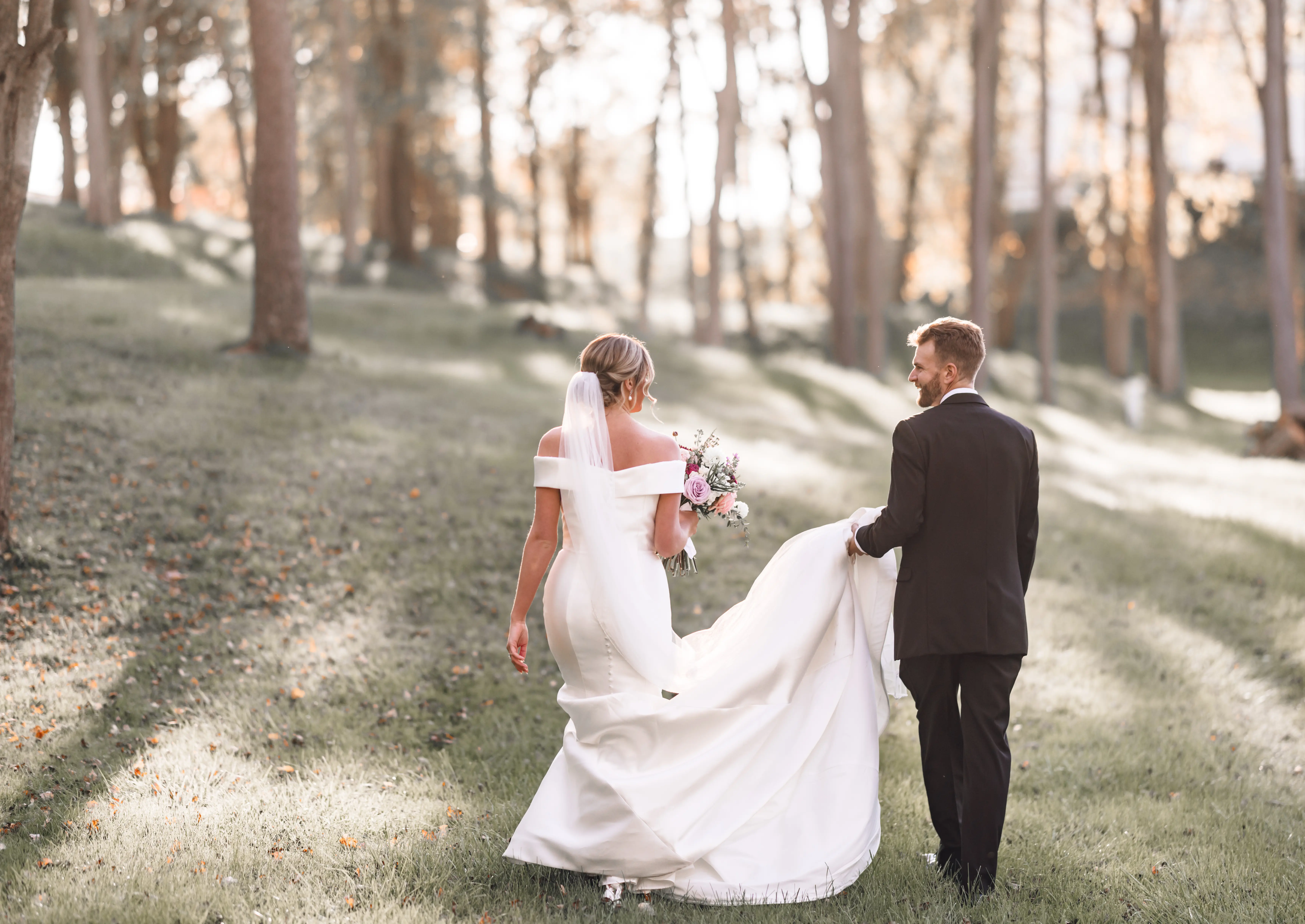 Groom Walking With Bride In A Timeless Fit And Flare Wedding Dress Named Josie By Rebecca Ingram