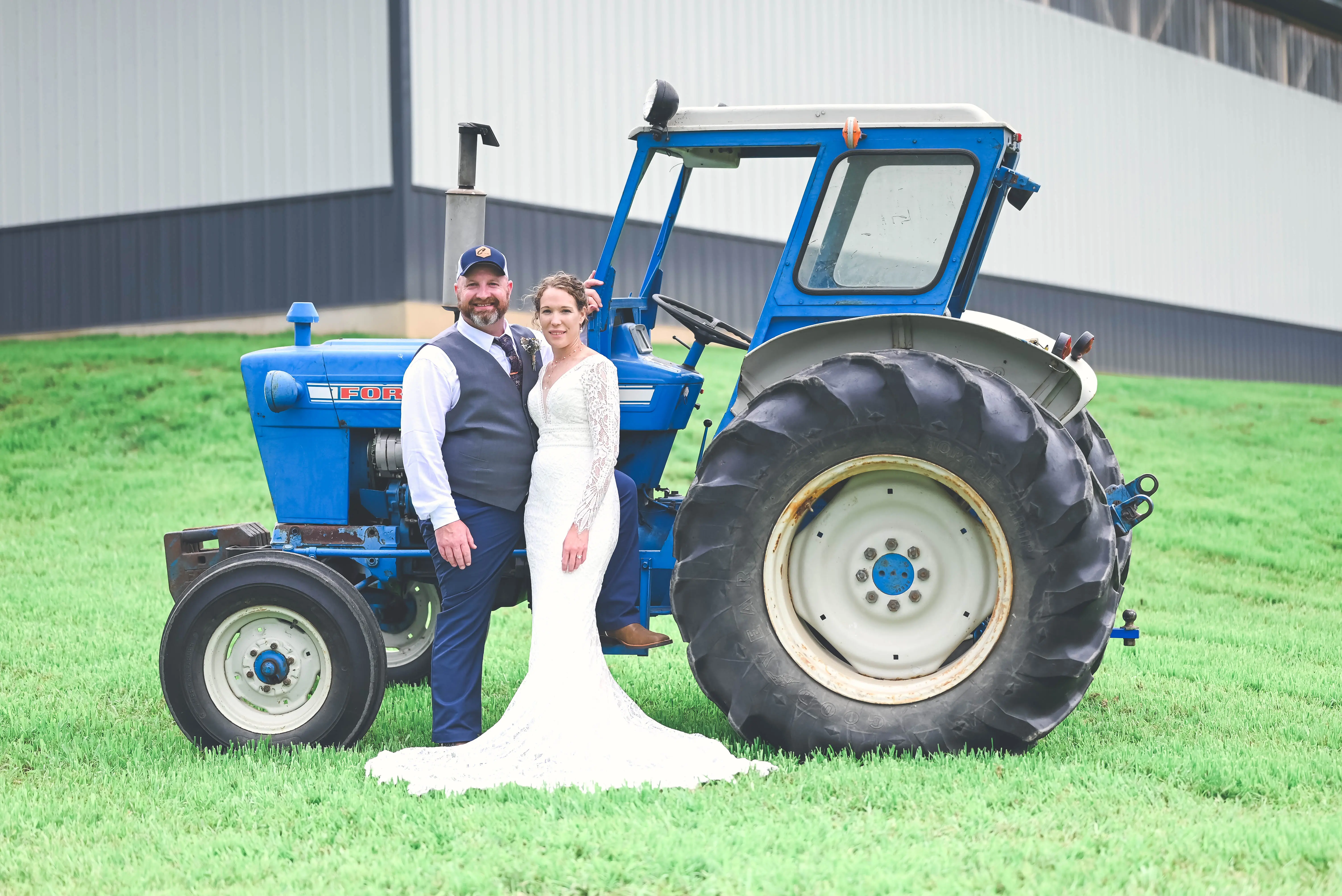 Bride wearing Drita wedding dress by Maggie Sottero with her husband in front of a tracktor
