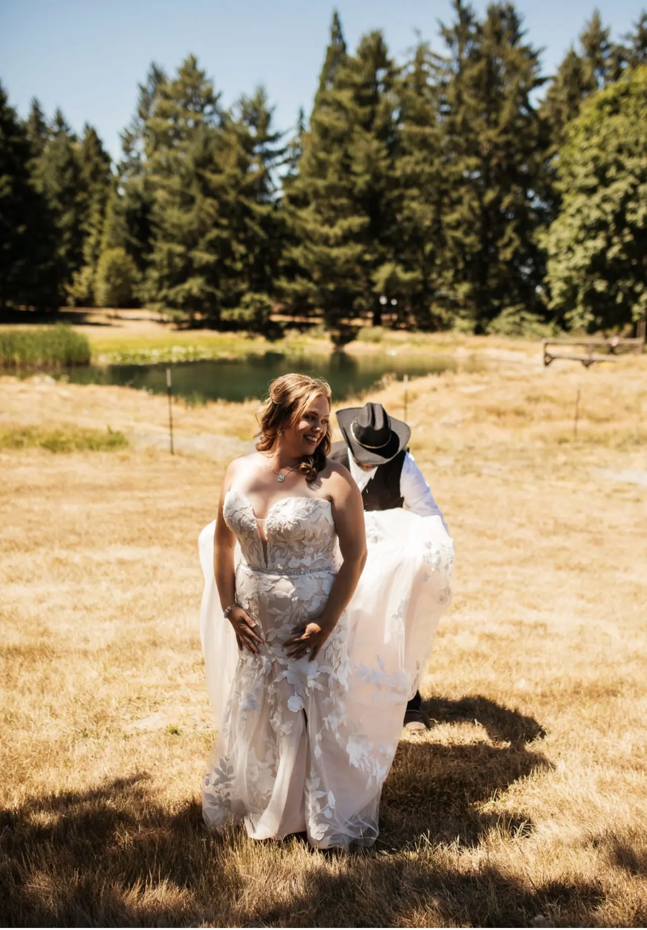 Bride wearing Hattie wedding dress by Rebecca Ingram getting train fixed by husband