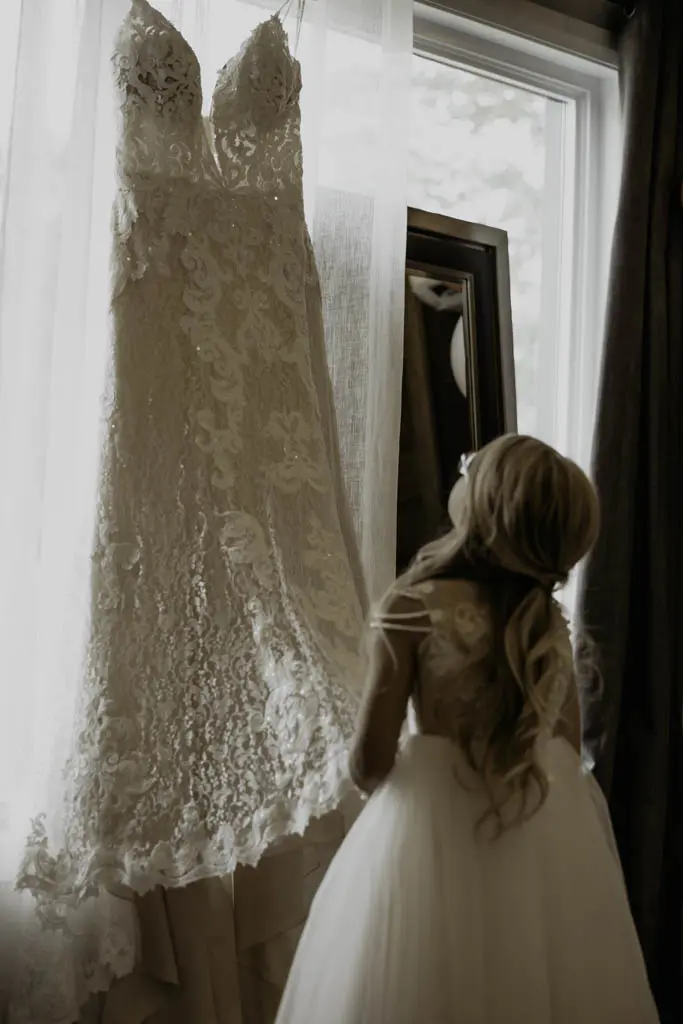 Flower Girl Admires Lace A-Line Wedding Dress Called Tuscany Lane By Maggie Sottero On Hanger