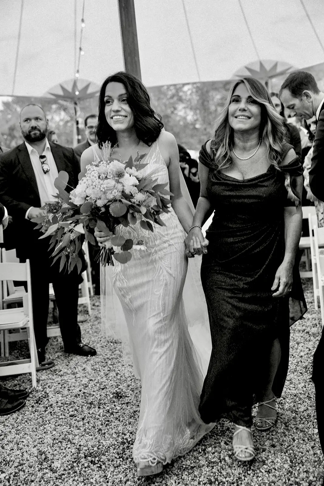 Bride wearing Luella wedding dress by Sottero and Midgley walking down the aisle with her mother