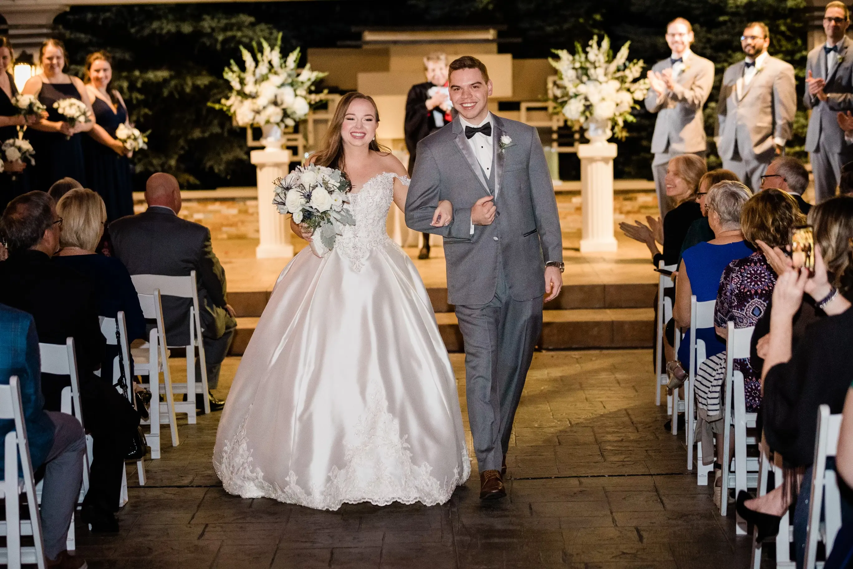 Bride And Groom Walking Down Aisle. Bride Wearing Satin Sparkly Ballgown Called Kimora By Sottero And Midgley