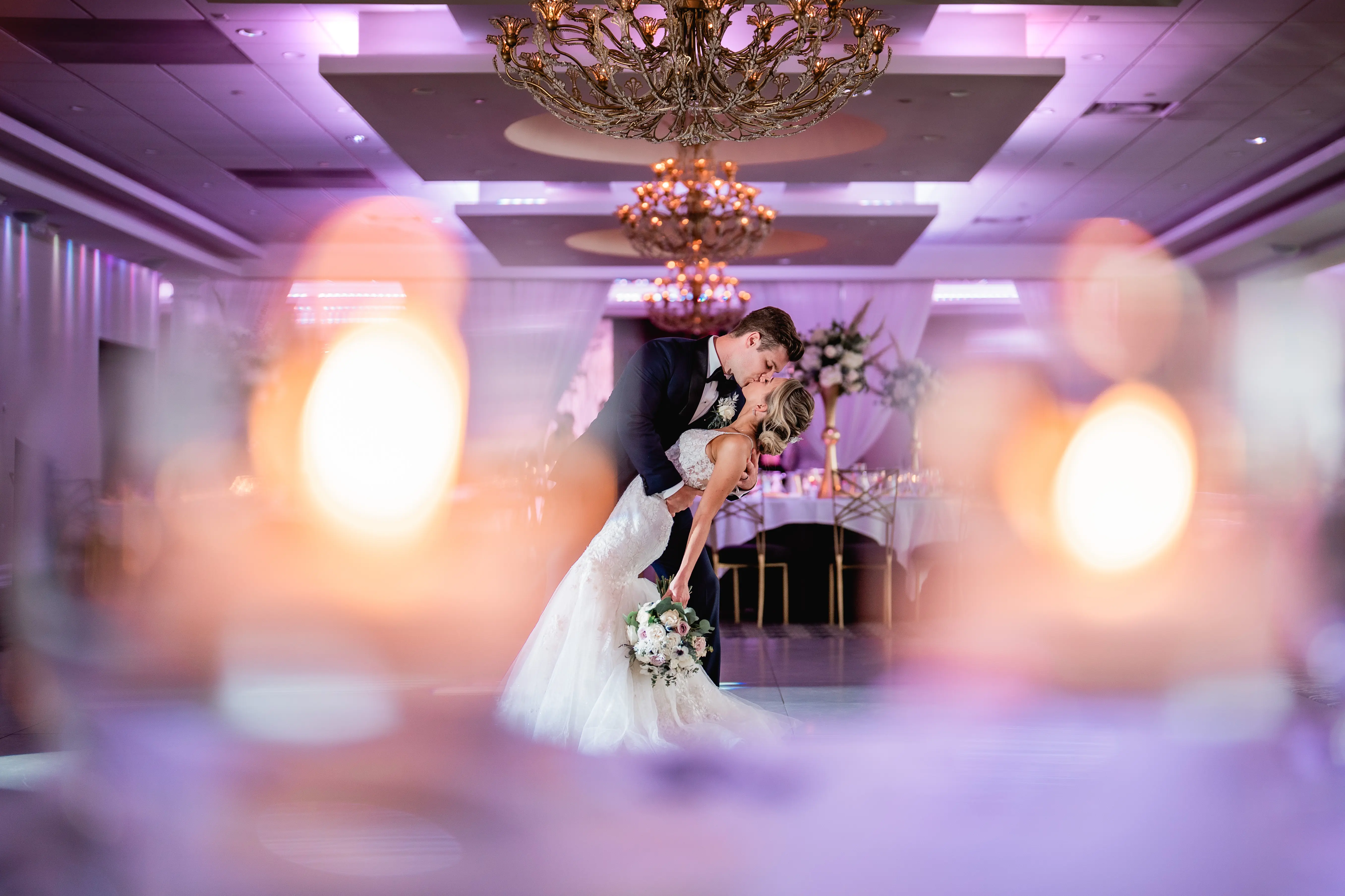 Groom dipping his bride on dance floor kissing her.