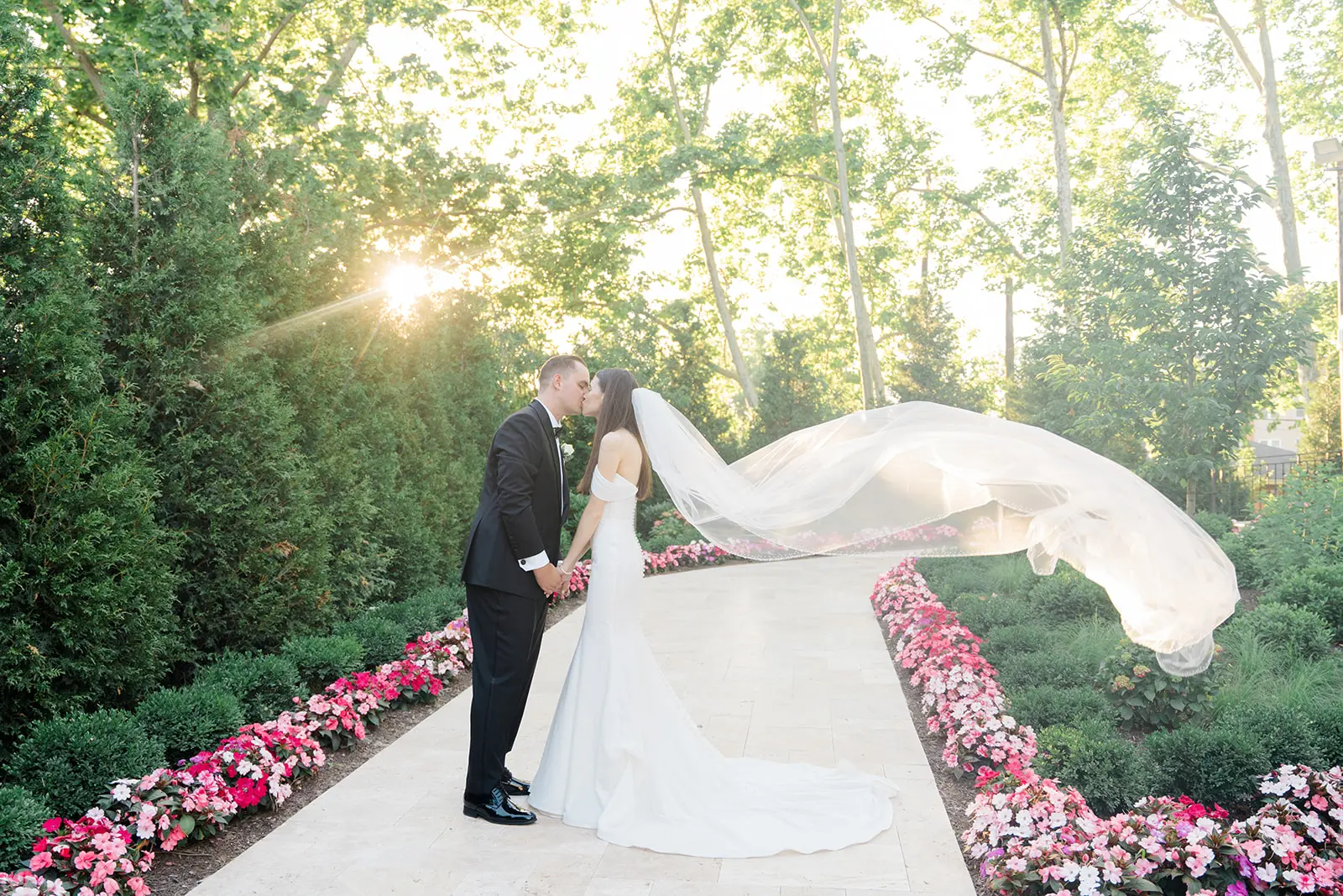 Bride wearing Anniston Lane by Maggie Sottero kissing her husband with the wind in her veil