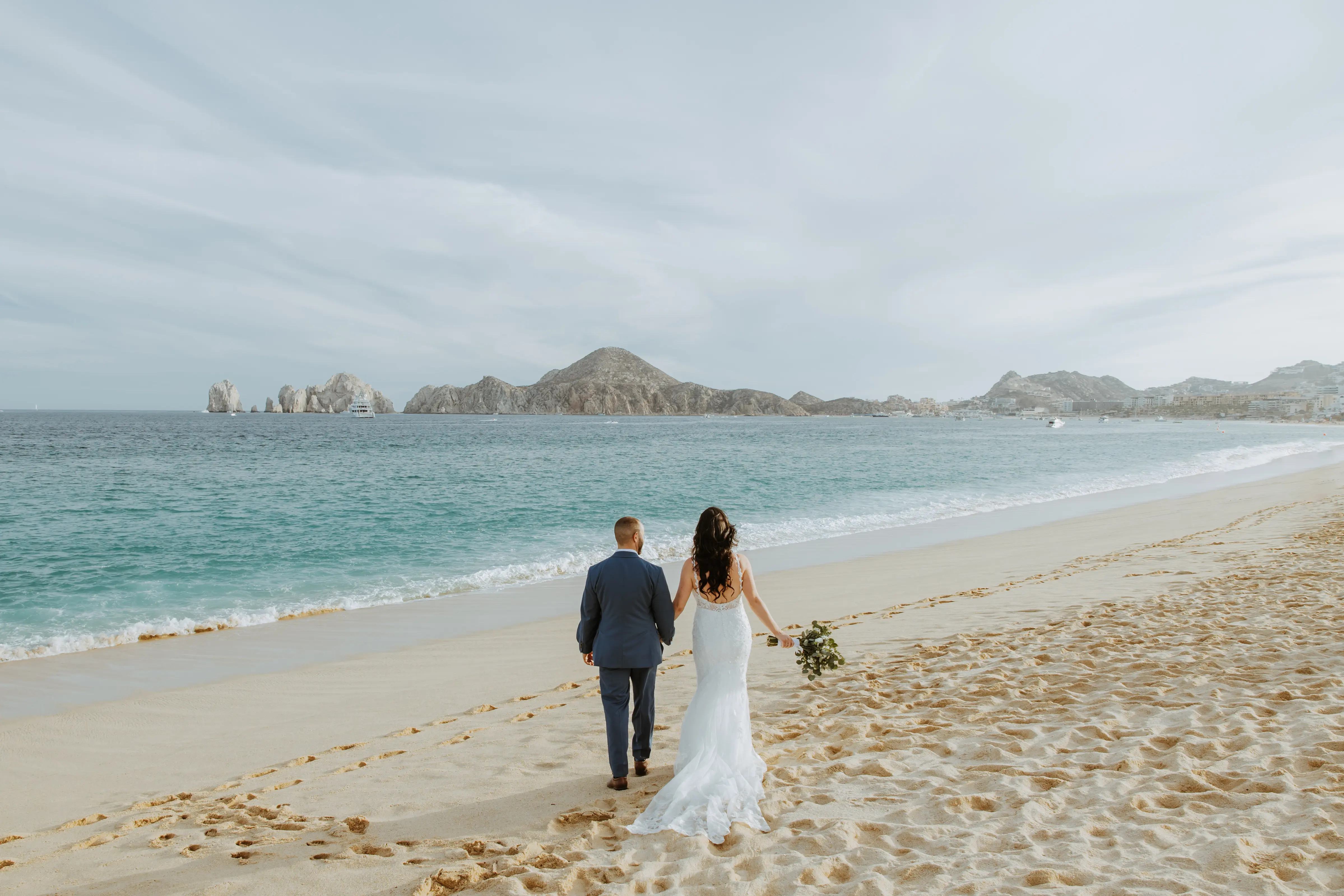 Groom Walking On Beach With Bride In A White Beaded Wedding Dress Named Jonah Lane By Sottero And Midgley
