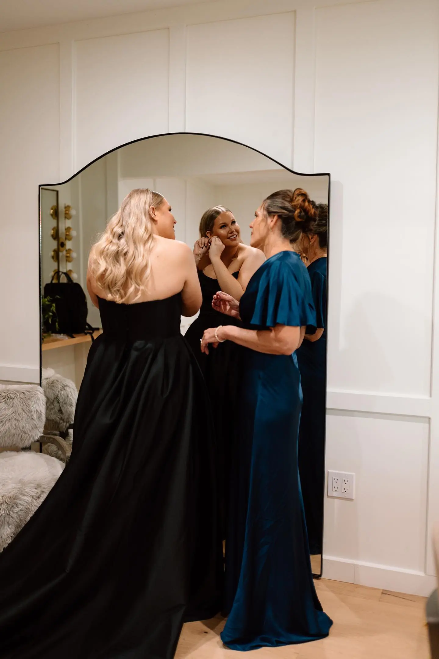 Bride wearing Aspen wedding dress by Sottero and Midgley putting on earrings