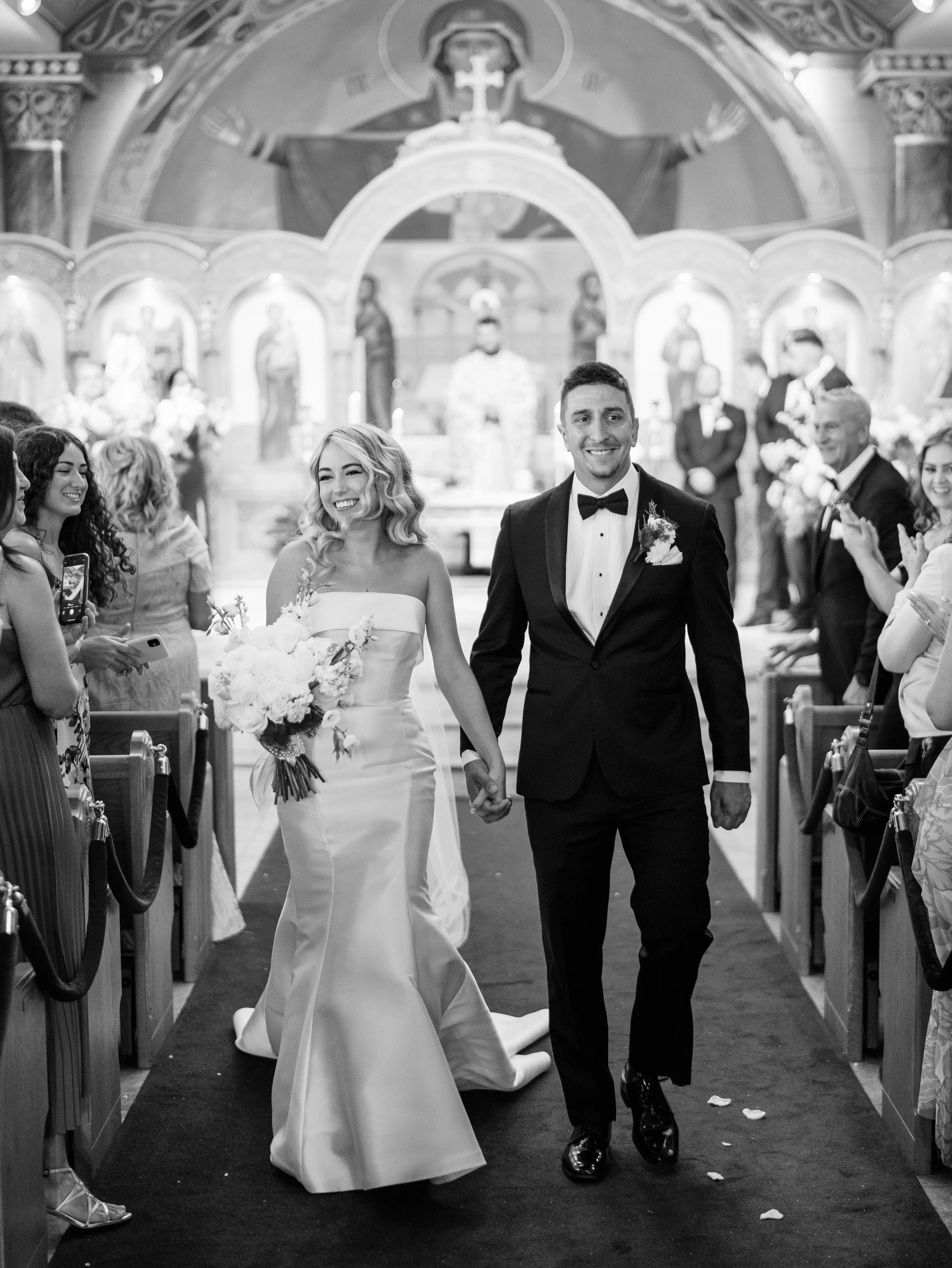 Bride Wearing Simple Fit And Flare Wedding Dress Called Mitchell Marie By Maggie Sottero Walking Down The Aisle With Groom