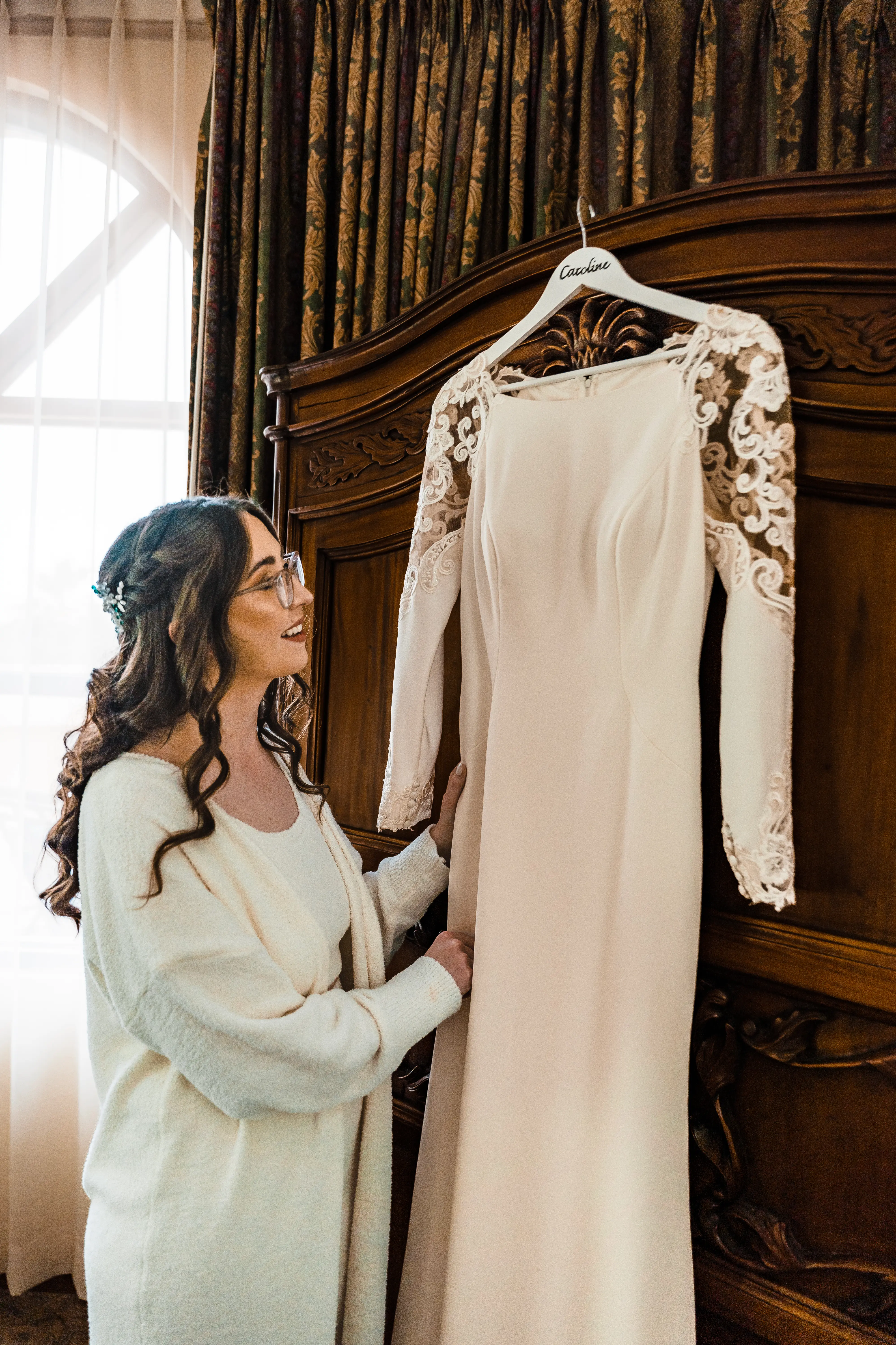 Bride Looking At Her Simple Long Sleeve Wedding Dress Called Bethany By Rebecca Ingram