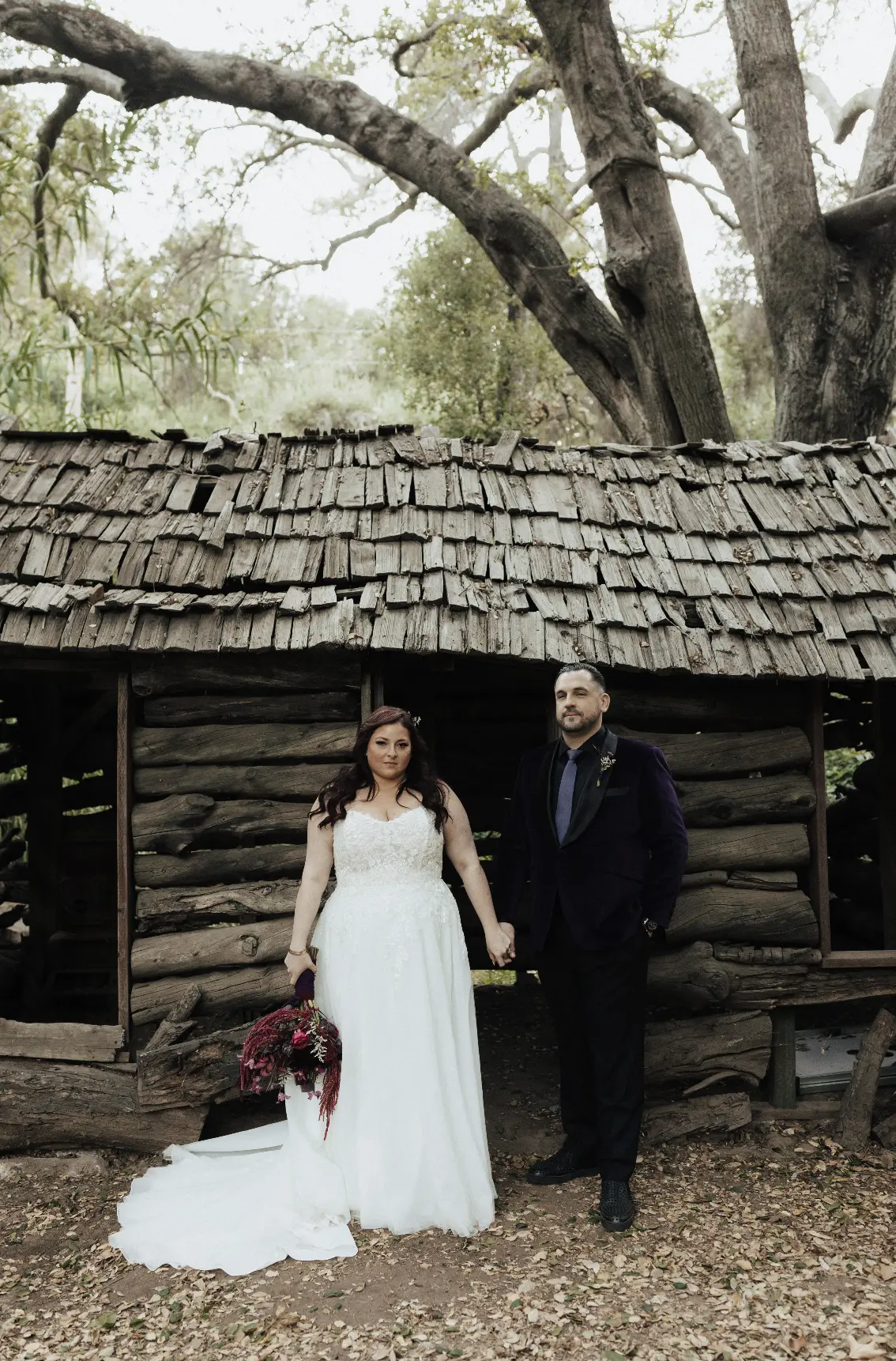 Bride Wearing A-line Bridal Dress Ainsleigh By Rebecca Ingram Holding Hands With Groom Next To An Abandoned Shed