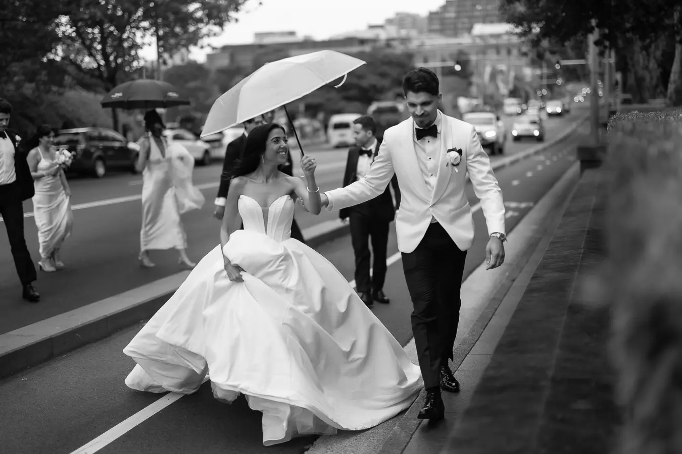 Bride wearing Derrick by Maggie Sottero walking in the rain with her husband