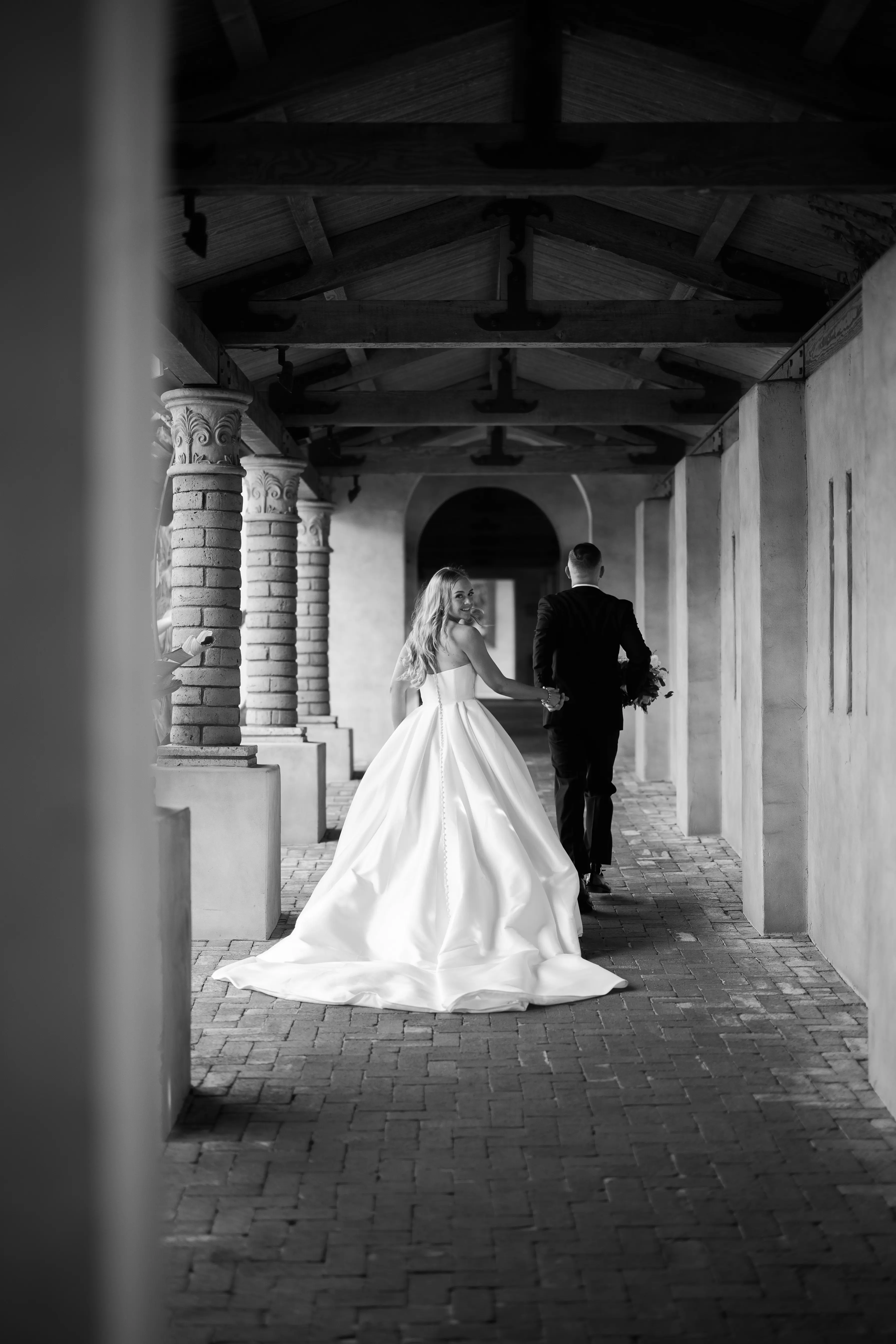 Bride wearing Aspen wedding dress by Sottero and Midgley walking away with groom