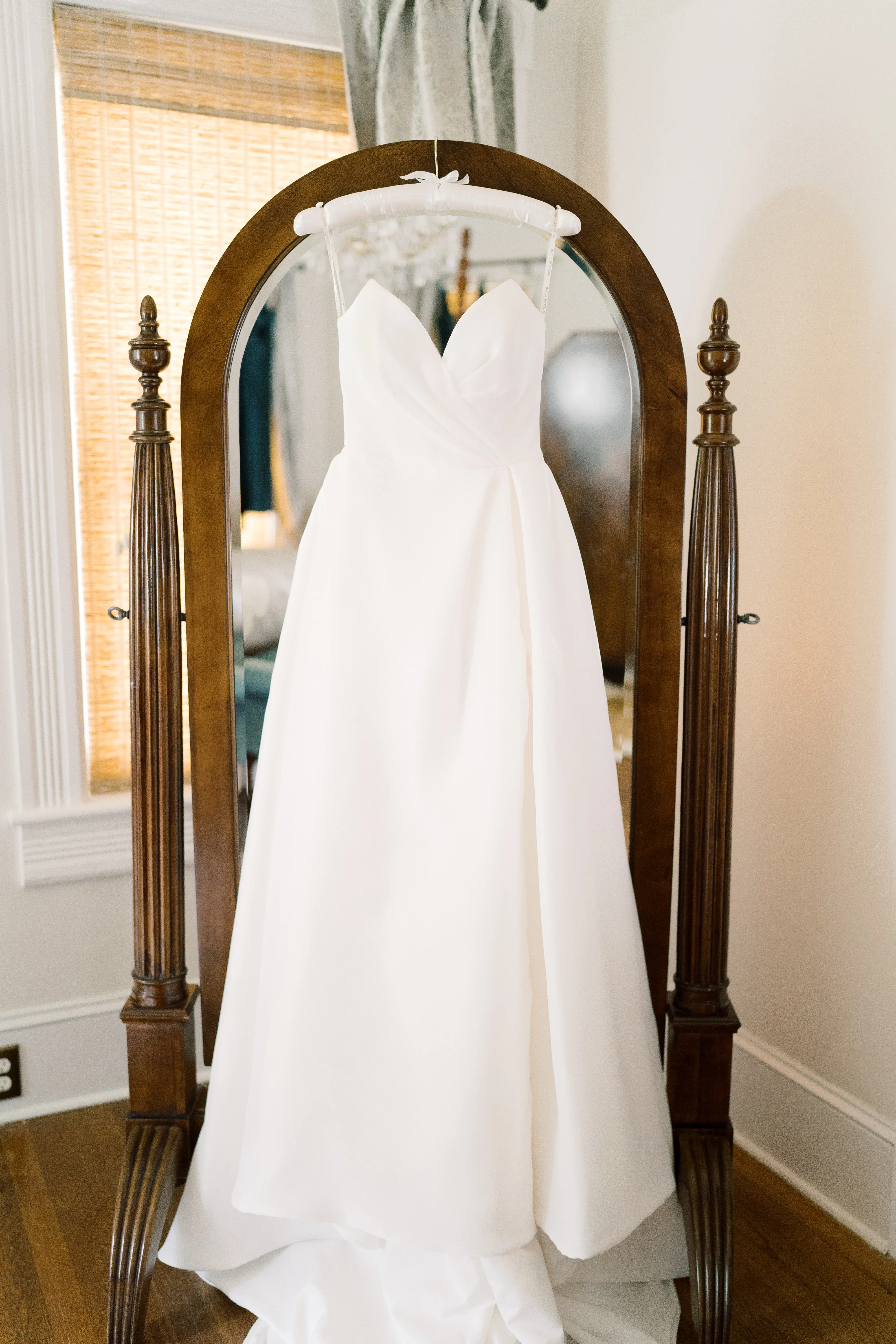 Nisha by Maggie Sottero hung over a mirror