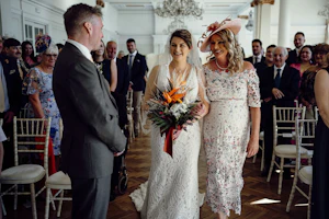 Bride Wearing Boho Lace Wedding Dress Called Burke By Maggie Sottero Walking Down The Aisle With Mother Of The Bride