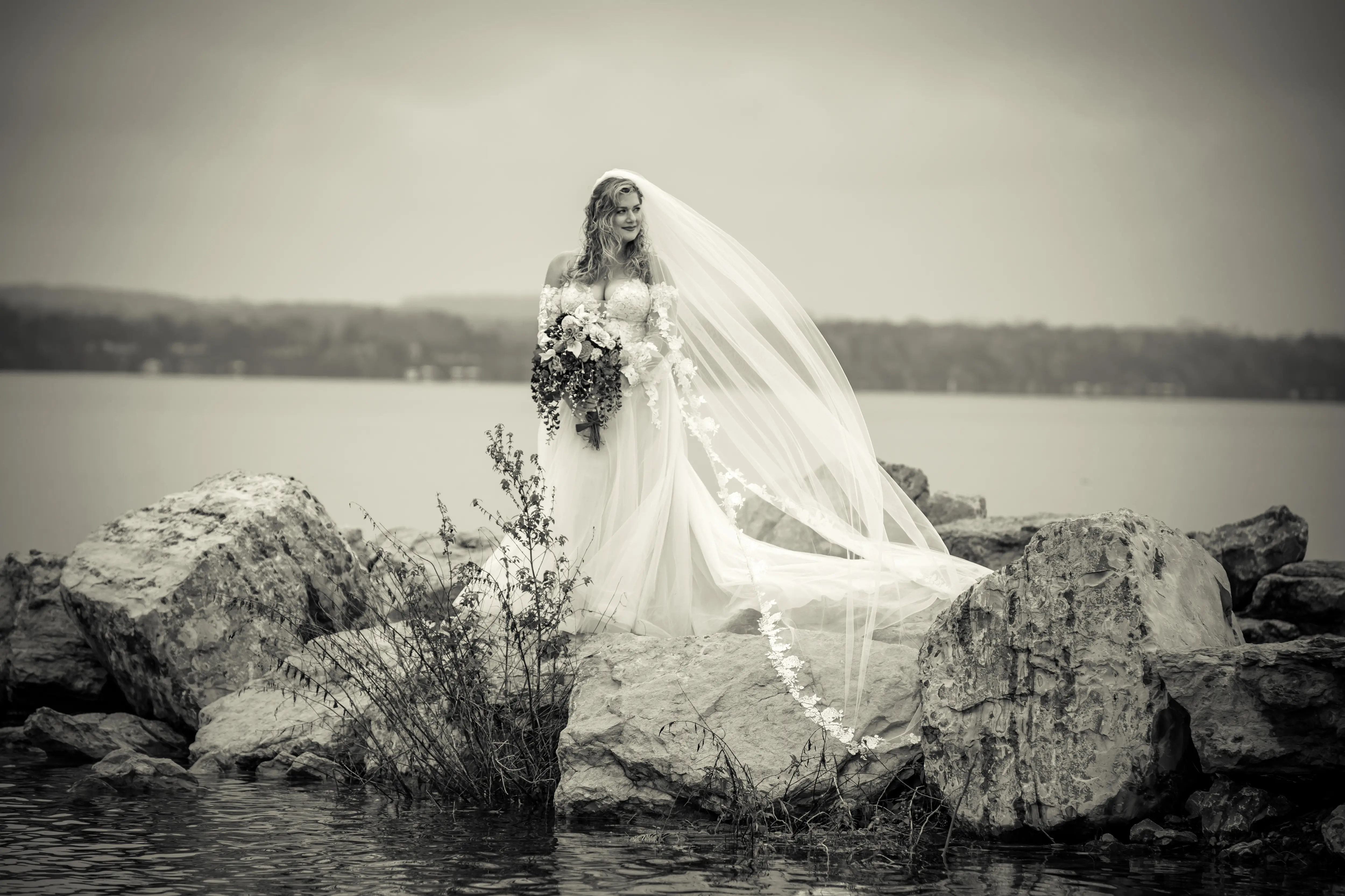 Bride Wearing Boho A-Line Wedding Dress Called Stevie By Maggie Sottero Standing On Rocks In A Lake