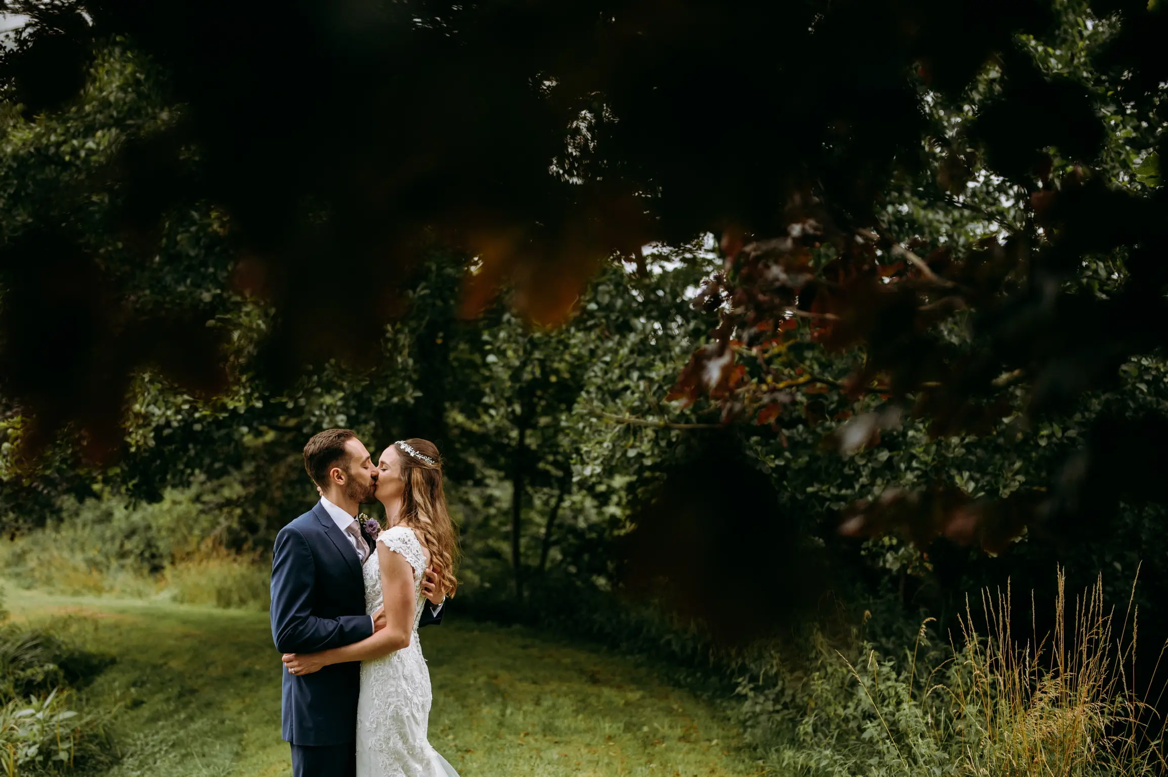 Groom kissing bride wearing wedding dress called Celeste.