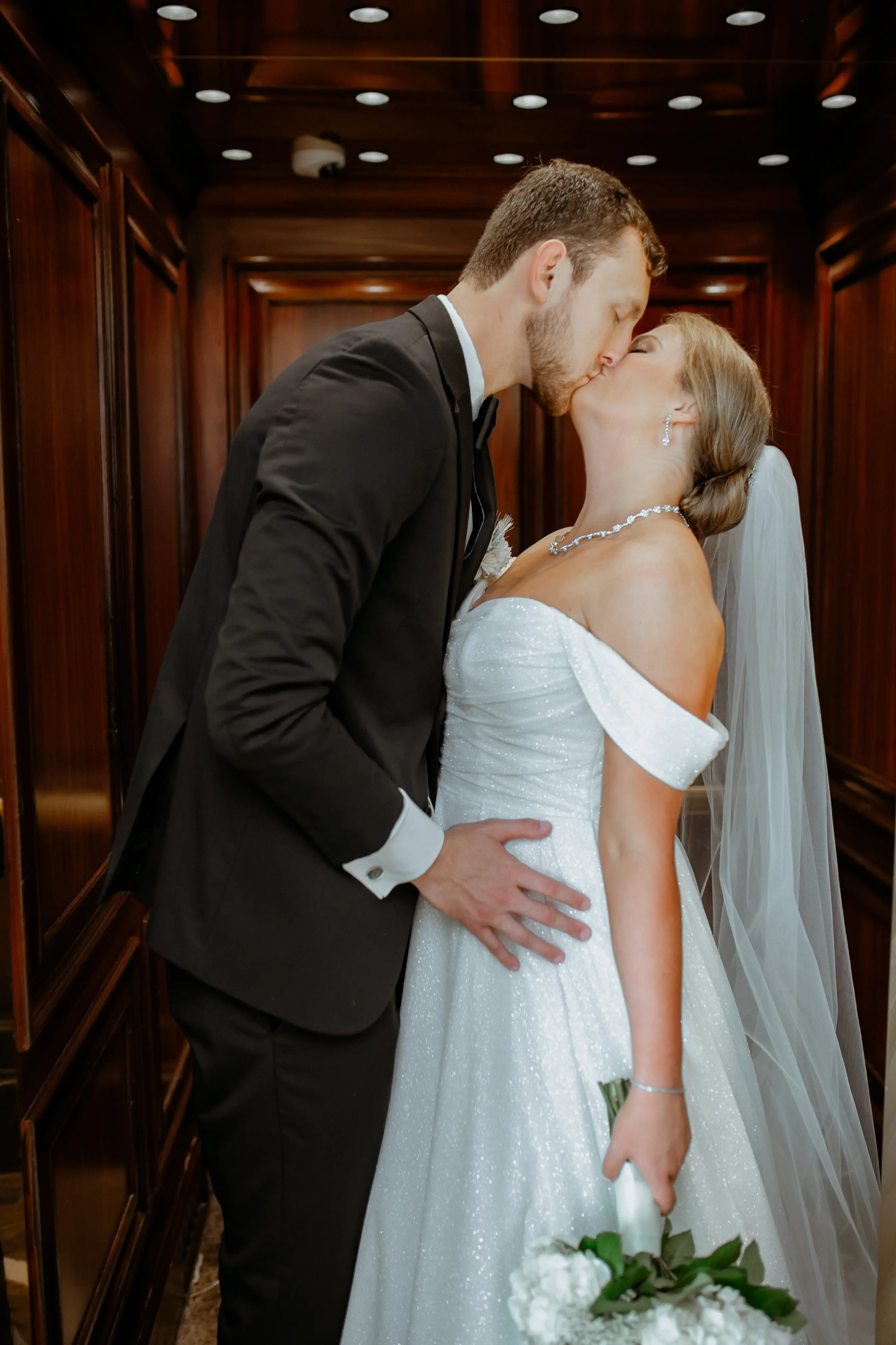 Bride wearing Anniston by Maggie Sottero kissing her husband in an elevator