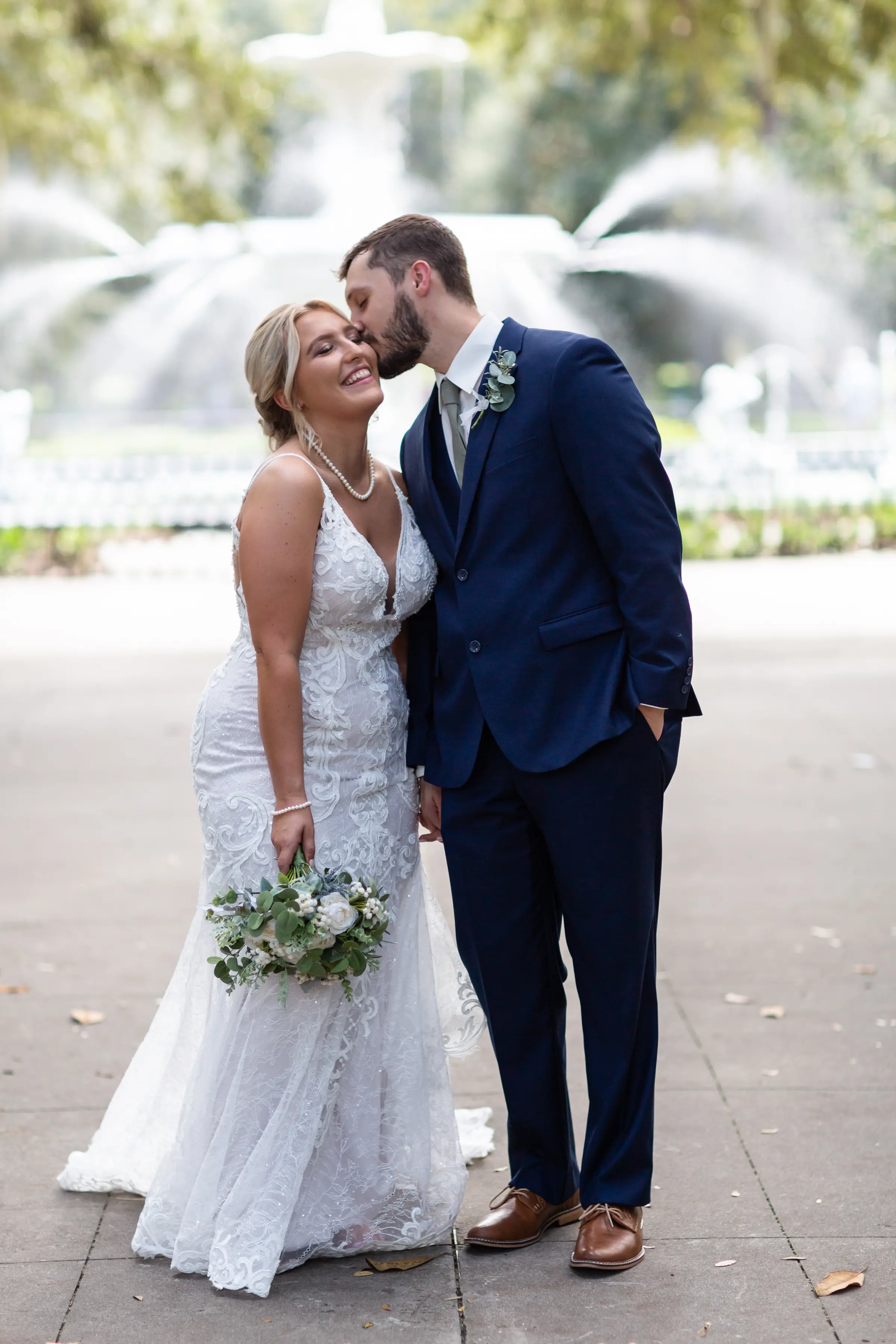Groom kissing his bride who is wearing wedding dress called Esther, on the cheek.