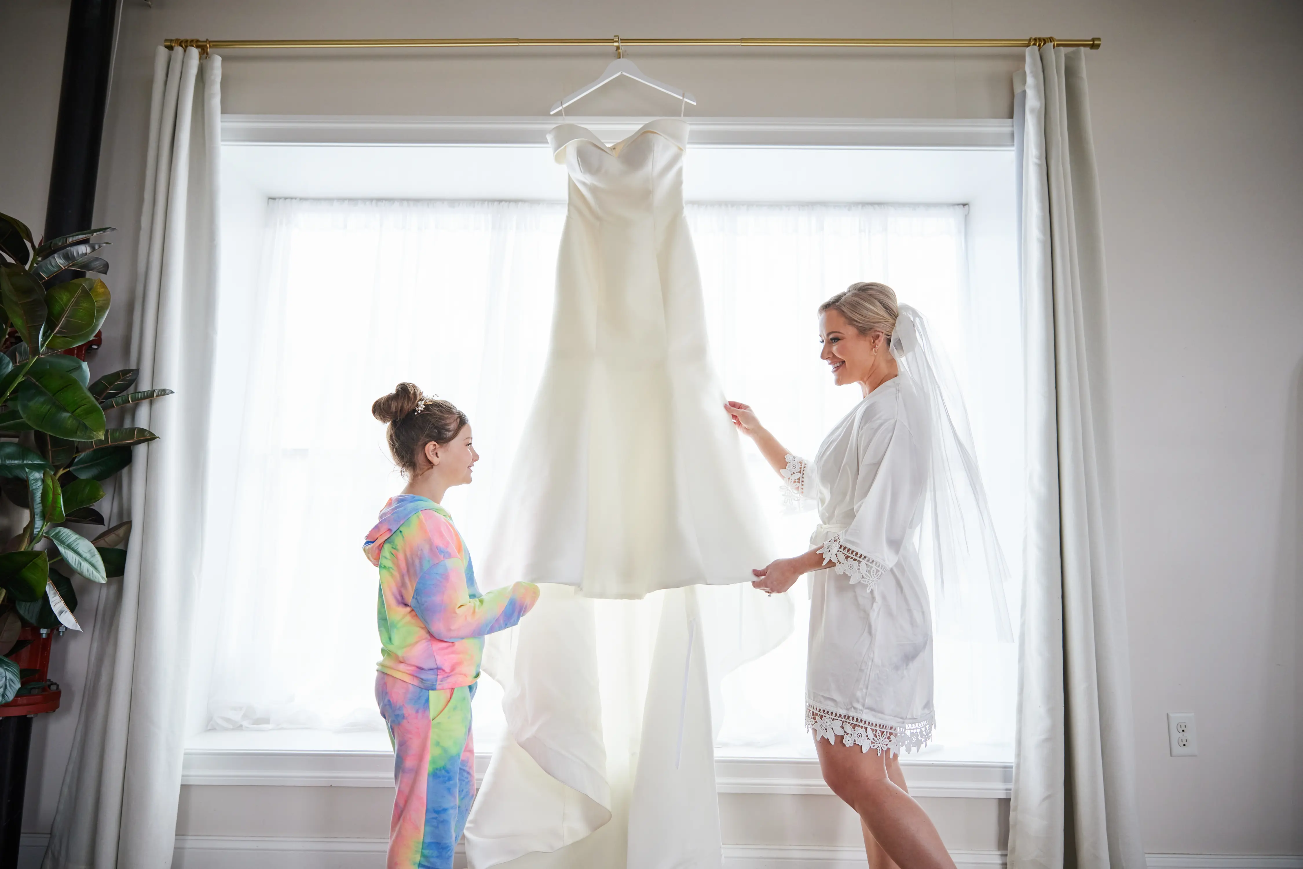 Bride Holding Wedding Gown in Window Called Josie by Rebecca Ingram.