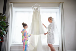 Bride Holding Wedding Gown in Window Called Josie by Rebecca Ingram.