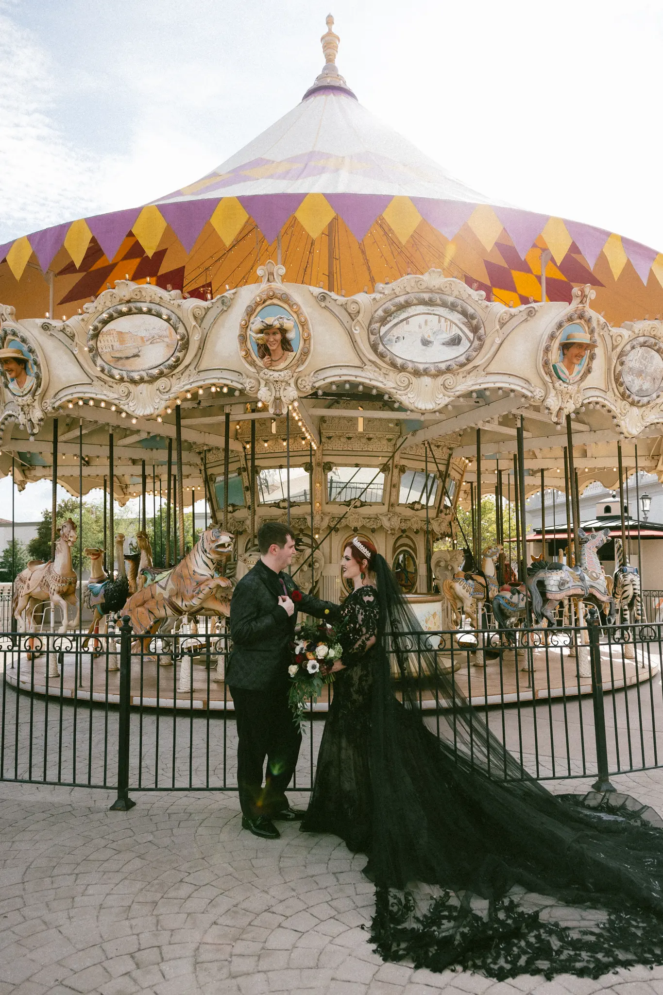 Bride Wearing Black Lace Wedding Dress Called Zander Lane By Sottero And Midgley With Groom In Front Of A Carousel