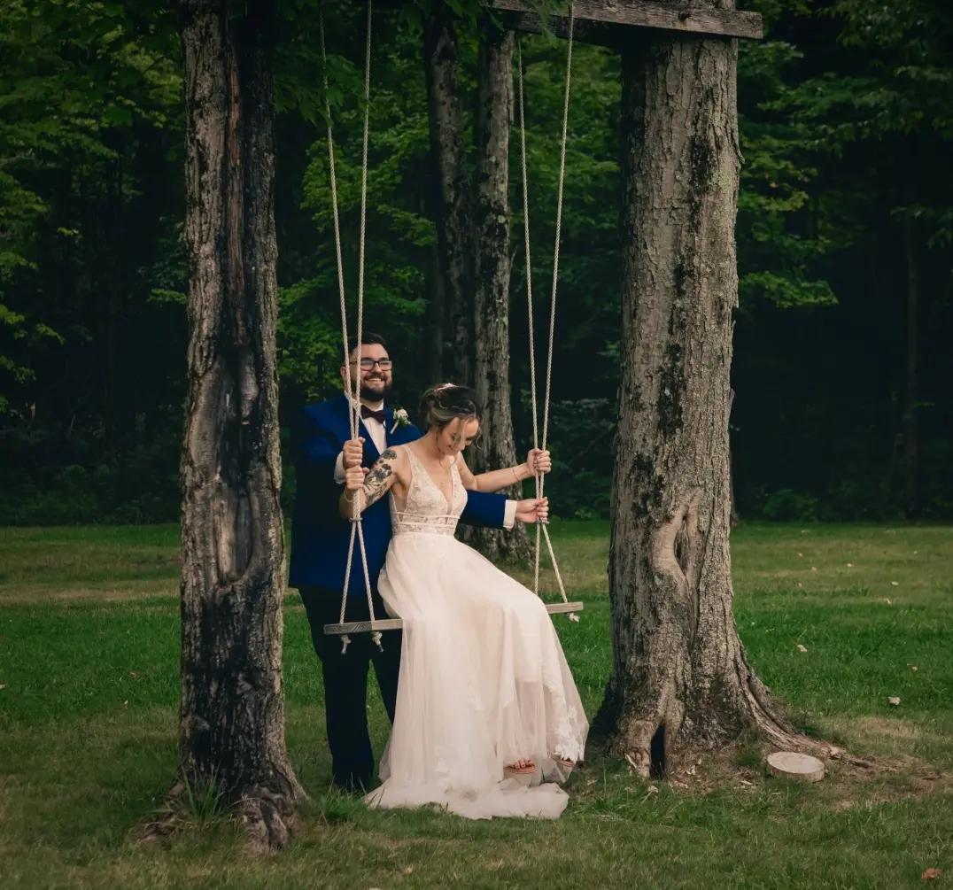 Bride wearing Boho Lace Wedding Dress called Raelynn by Rebecca Ingram sitting on a swing with the groom