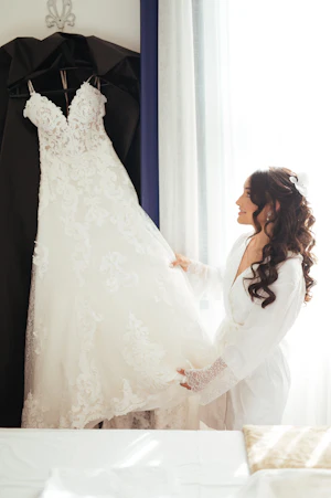 Bride Admiring Flattering Full Lace Wedding Dress Called Tuscany Lane By Maggie Sottero On A Hanger