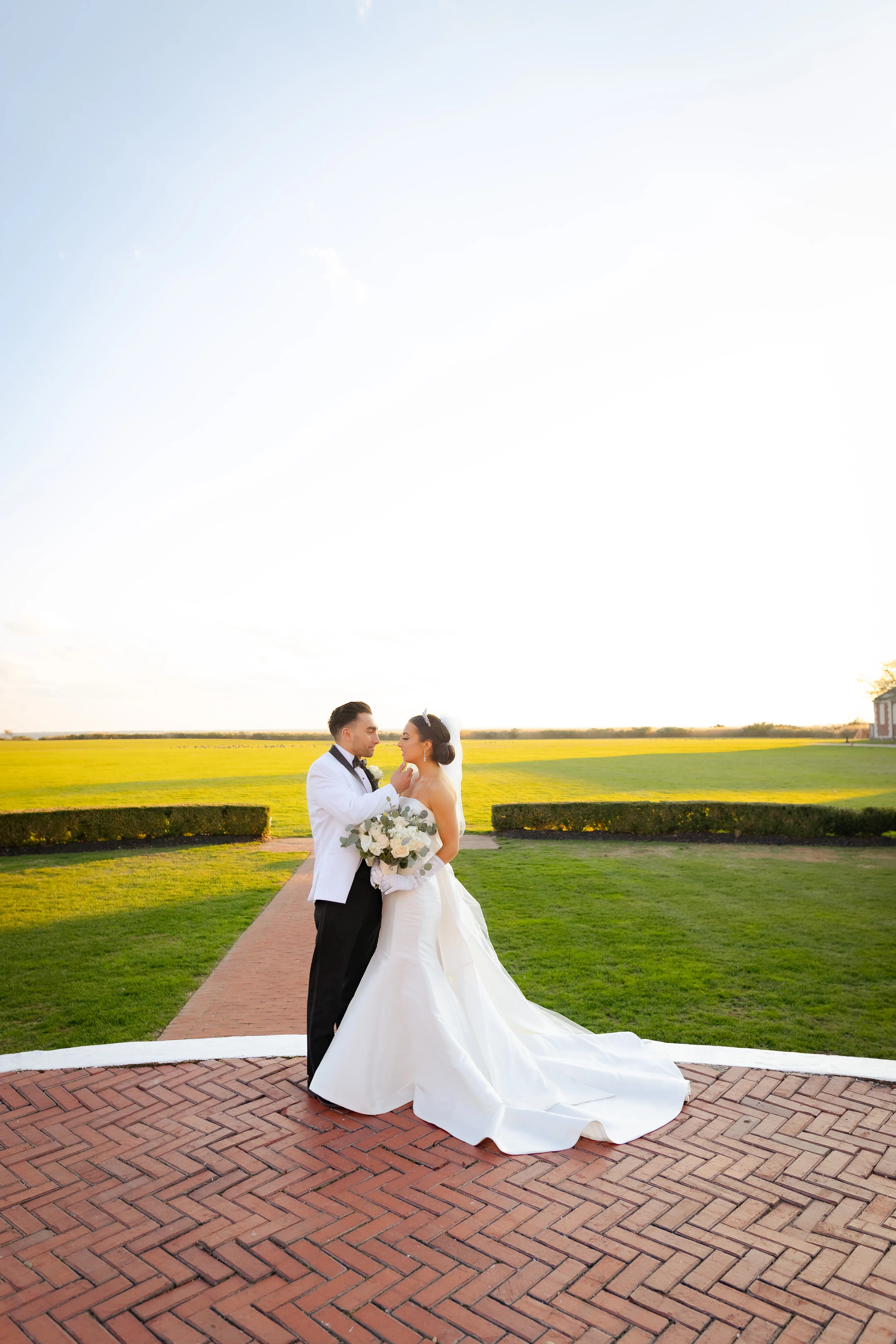 Bride And Groom Standing Together. Bride Wearing Unique Strapless Wedding Gown With Statement Bow Called Mitchell By Maggie Sottero