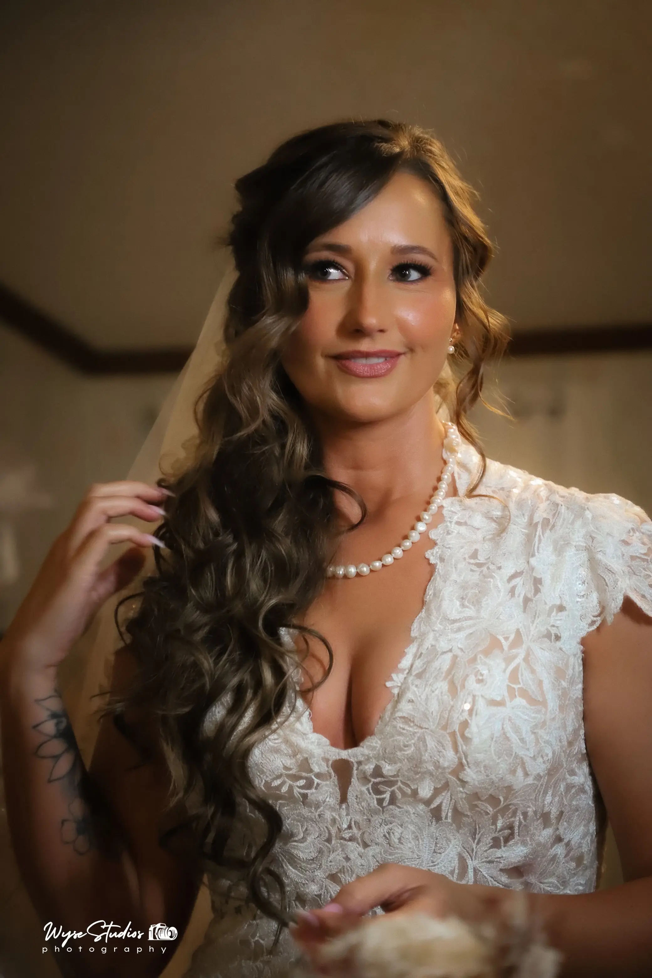 Bride wearing Kingsley wedding gown by Sottero and Midgley fixing her hair