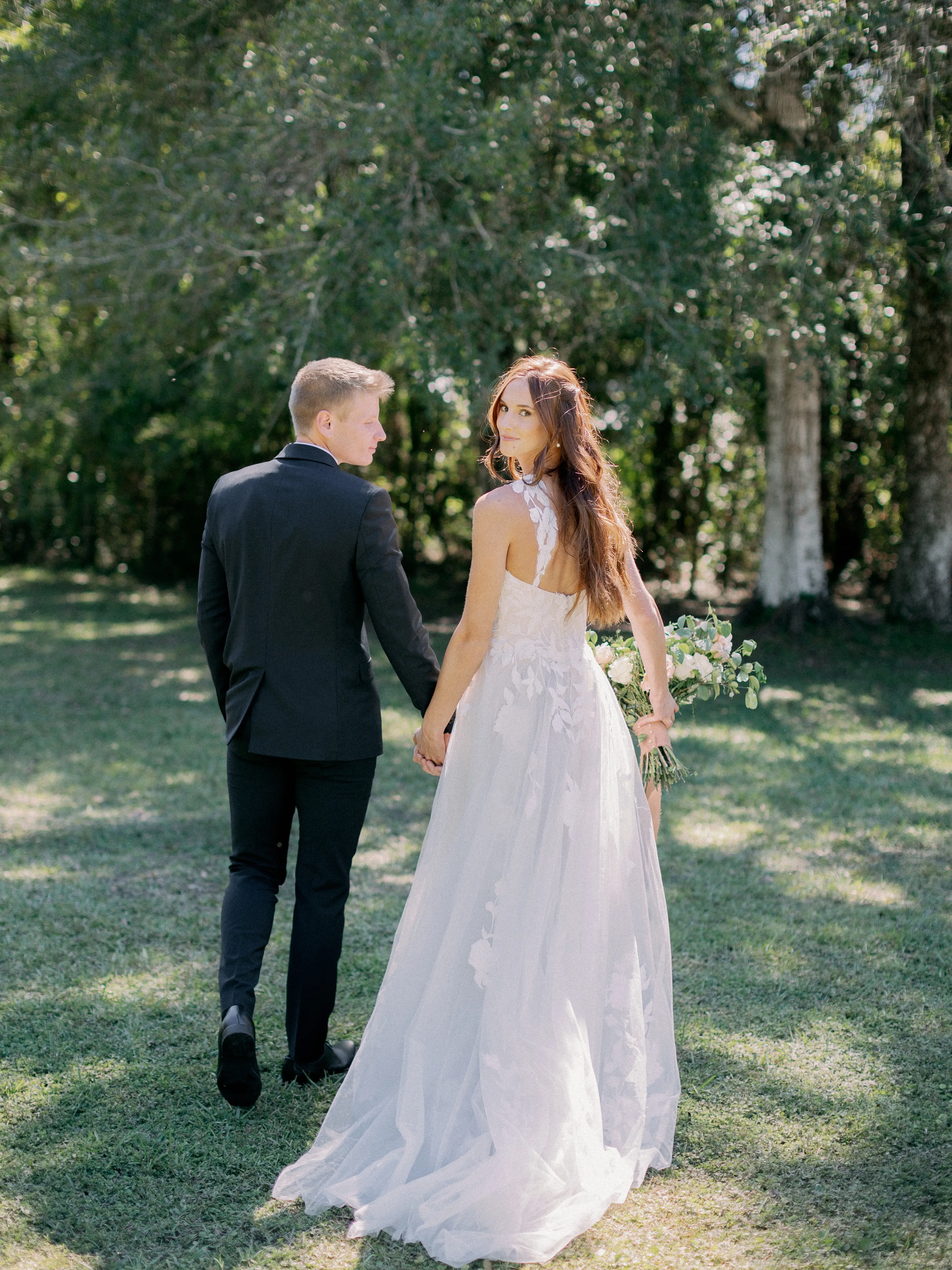 Bride Wearing Plunging V-Neckline Bridal Dress Named Hattie Lane Marie By Rebecca Ingram Bride and Groom Looking Back to Camera