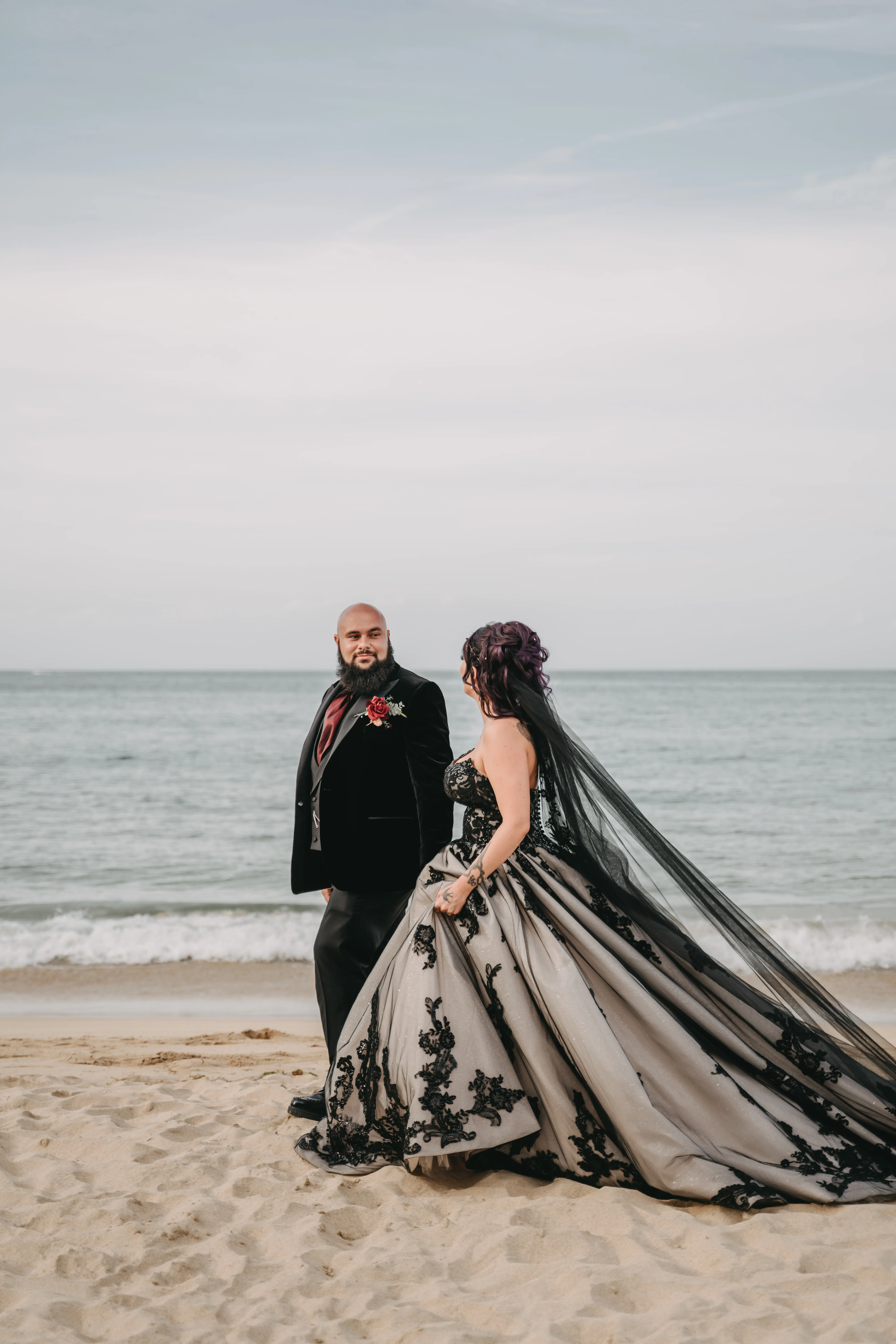 Bride wearing Norvinia by Sottero and Midgley walking on the beach with her husband
